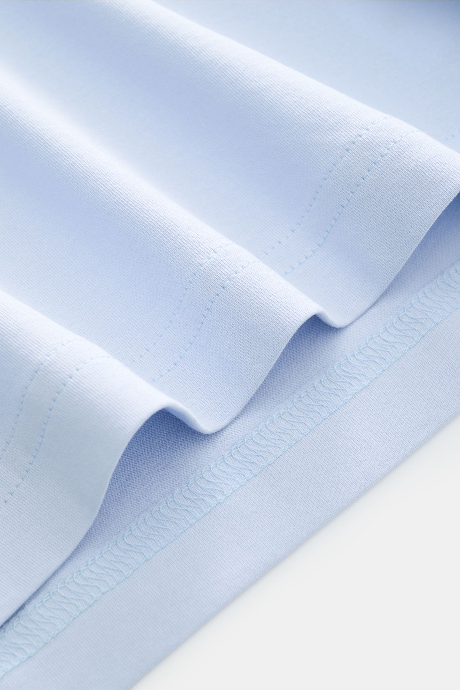 Close-up from above of the light blue fabric and hem of the Stefan Brandt V-Neck T-Shirt 'Artur' hellblau, made from soft 'Urpima Sea Island' cotton jersey with slim fit and V-neck. Luxuriöses Essential: Das V-Neck T-Shirt 'Artur' von STEFAN BRANDT aus