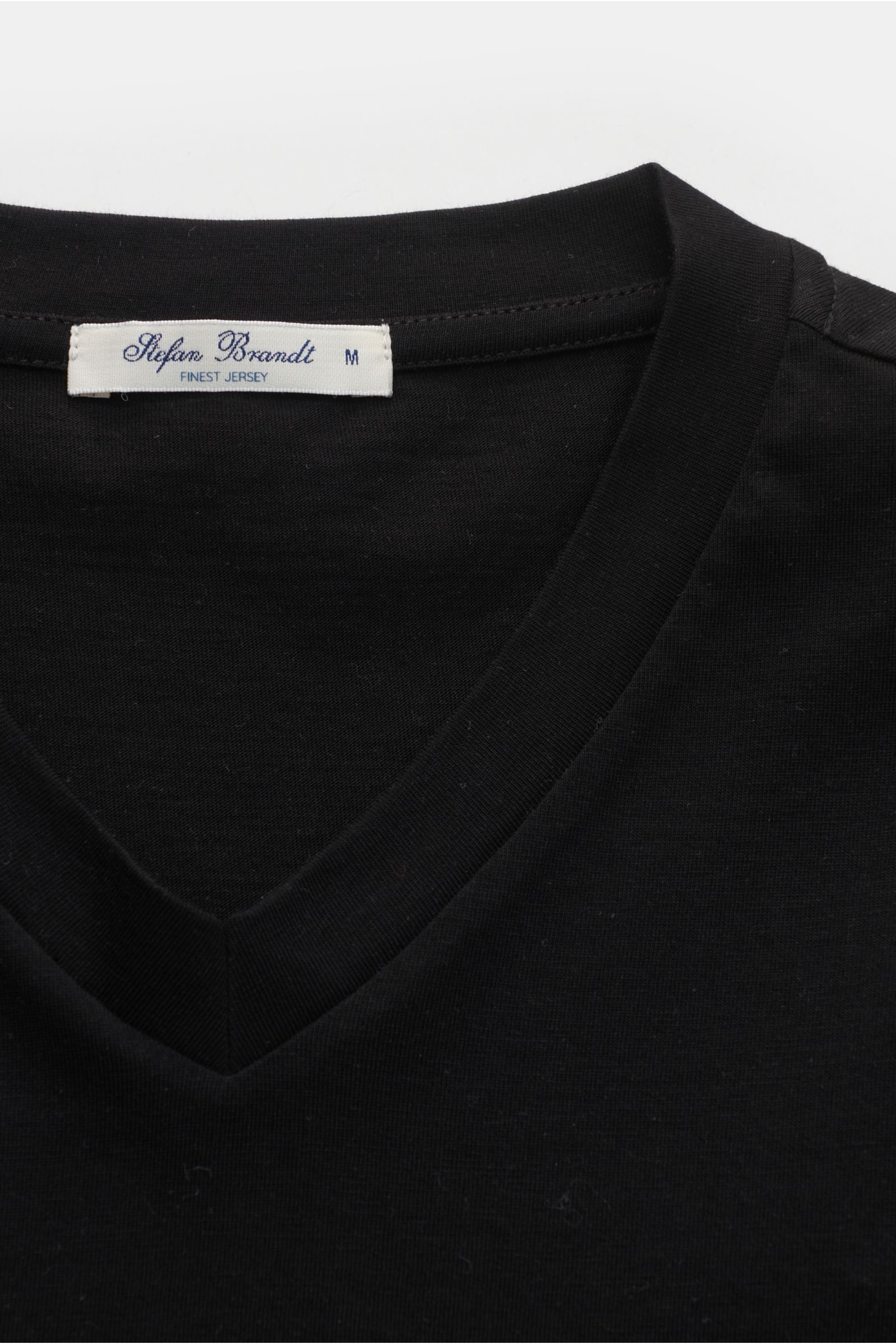 Close-up front view of the Stefan Brandt V-Neck T-Shirt 'Adam' schwarz, showcasing its slim fit, soft black Jersey fabric from pure 'Urpima Sea Island' cotton, and V-neckline with label visible. 

Luxuriöses Essential: Das V-Neck T-Shirt von STEFAN BRA