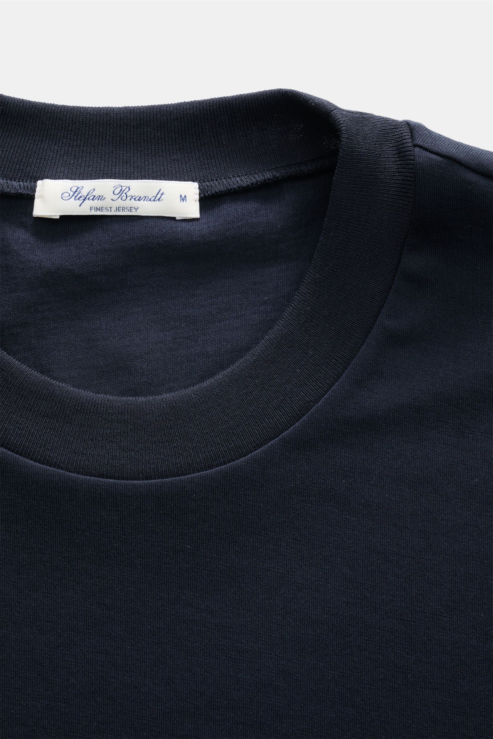 Close-up top view of the Stefan Brandt Rundhals-T-Shirt 'Eli' navy showing the round neckline and label. Jersey in seiner feinsten Qualität: Mit seinem Expertenwissen über Materialien schafft STEFAN BRANDT das T-Shirt 'Eli' aus reiner 'Urpima Sea Island' 