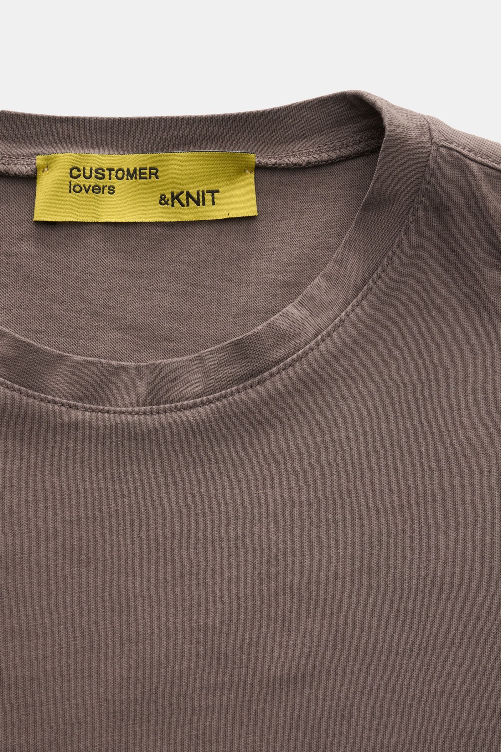 Close-up front view of the B.F. Knitwear Crew neck T-shirt grey-brown showing the crew neck and fabric texture, made of pure cotton fabric in a precise slim fit with short hem vents, soft feel, ideal for spring and summer. 

Description: A high-quality