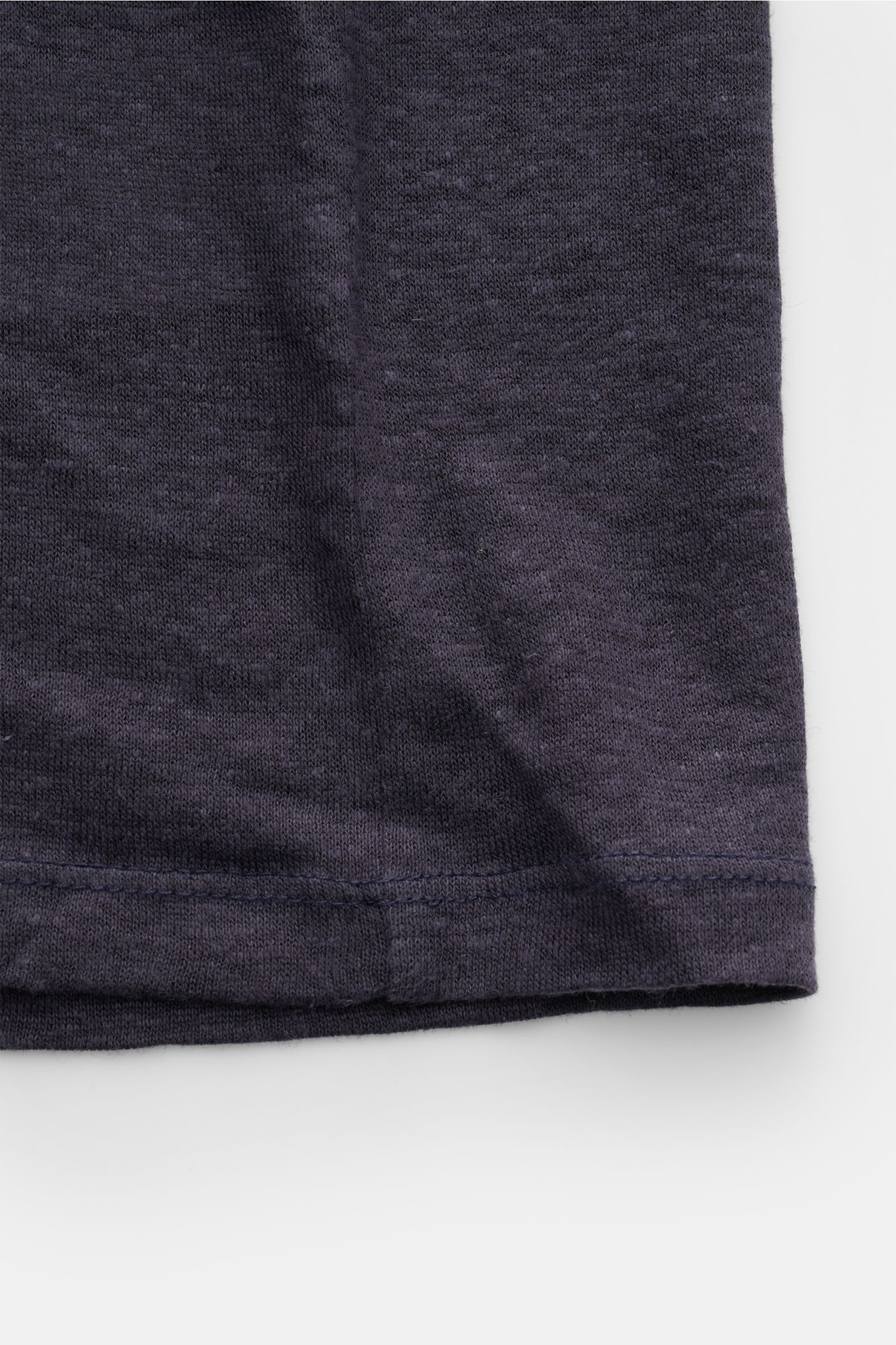 Close-up of the hem of the Officine Générale Leinen Rundhals-T-Shirt navy, showing soft, lightweight pure linen jersey fabric with garment-dyed slim fit and round neckline, photographed from a top-down perspective.

Die leichte Qualität aus reinem Lein