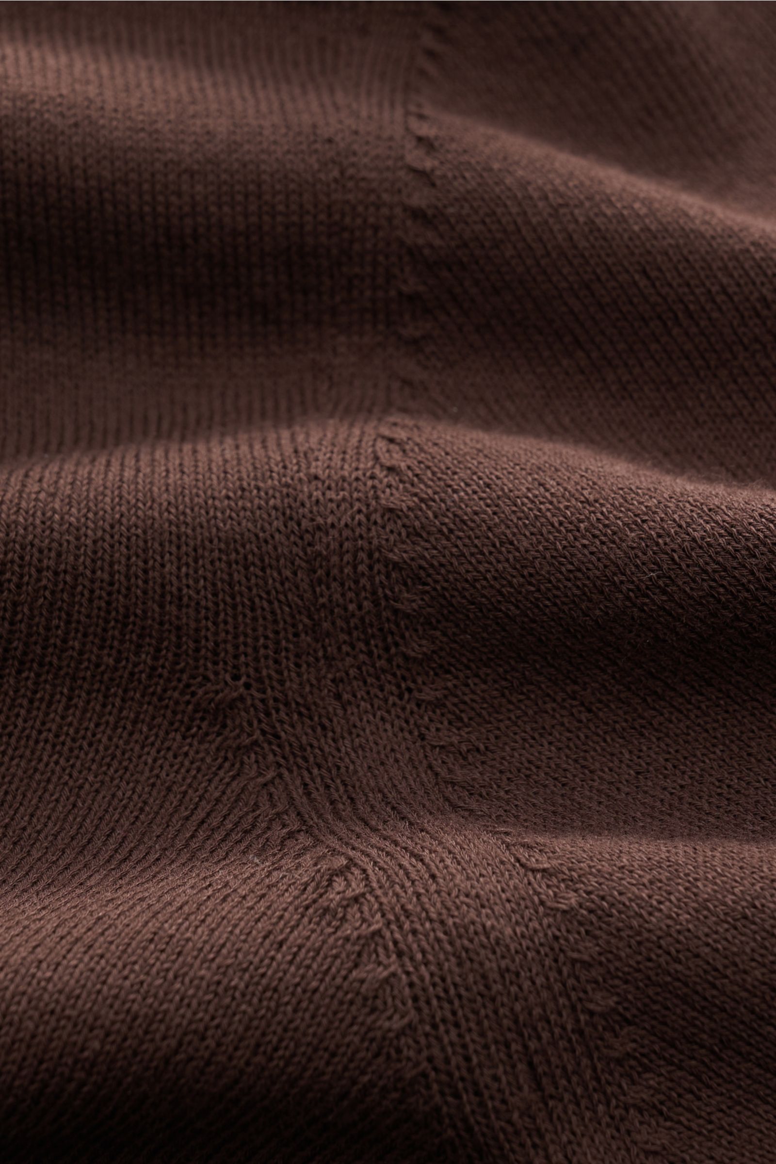 Nahaufnahme des Piacenza 1733 Kurzarmpullovers dunkelbraun, leichter Strick aus reiner Baumwolle mit feinem, offenem Strickbild und flexiblen Rippbündchen, Slim Fit, fotografiert aus schräger Perspektive.