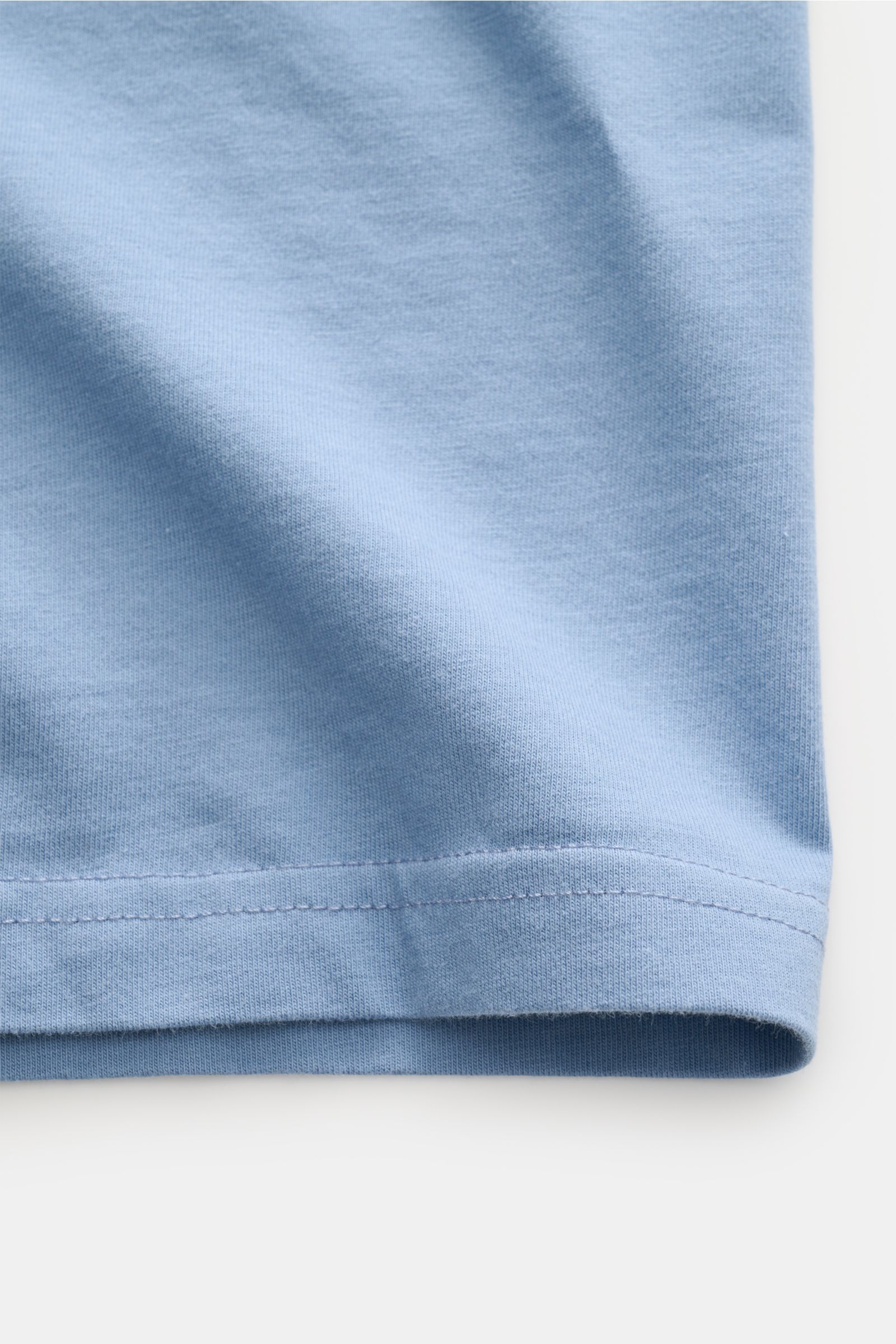 Close-up of the hem on the MC2 Saint Barth Crew neck T-shirt 'Portofino' smoky blue, showing soft organic cotton fabric and stitching.

Summery and eye-catching: This MC2 SAINT BARTH T-shirt, made from soft organic cotton, features eye-catching chest s
