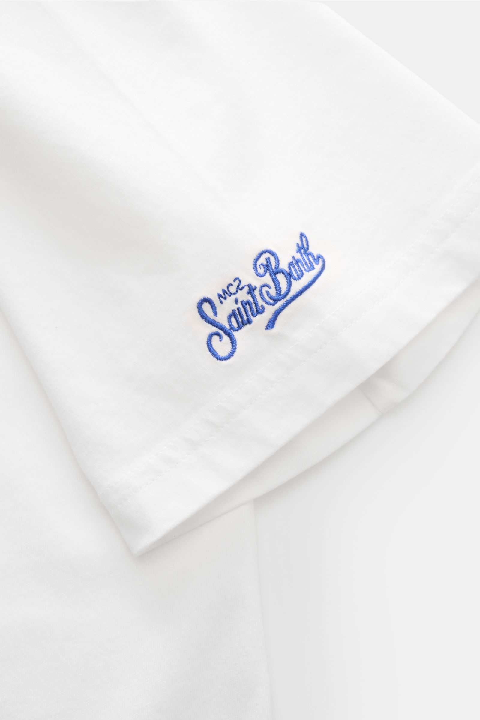 Close-up of the sleeve of the MC2 Saint Barth Rundhals-T-Shirt 'Portofino' weiß showing blue St. Barth embroidery on white organic cotton fabric.

Sommerlicher Hingucker: Das T-Shirt von MC2 SAINT BARTH aus weicher Bio-Baumwolle wird mit auffälligem Br