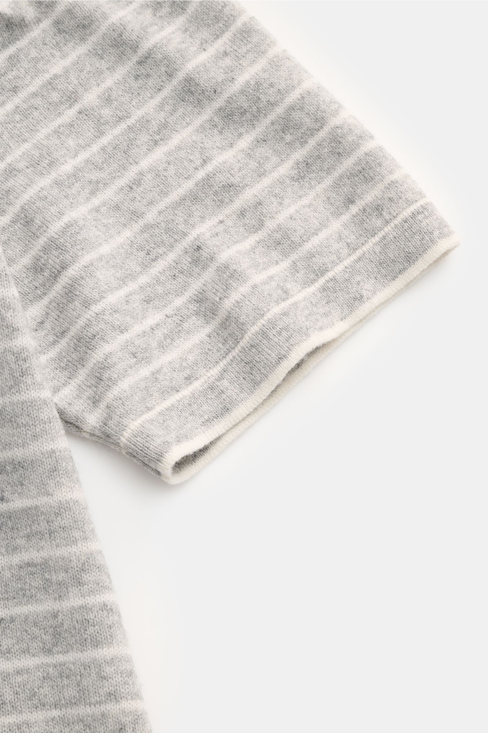Nahaufnahme des Ärmels vom FTC Kurzarm-Rundhalspullover grau/weiß gestreift aus luftigem Cashmere-Baumwoll-SeaCell-Mix mit feinem Strickbild, softem Material, rolliertem Saumabschluss und Regular Fit, fotografiert von schräg oben.