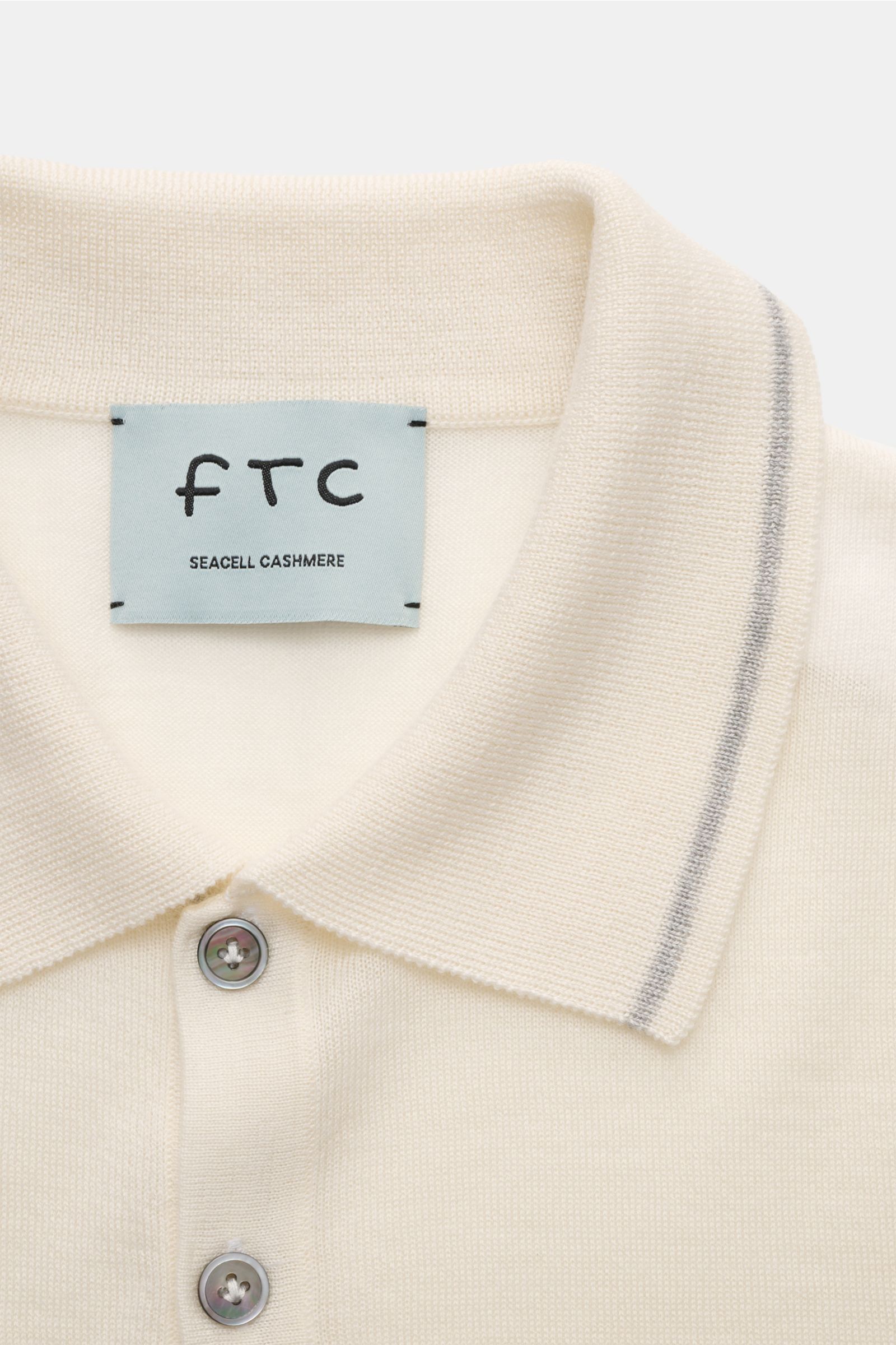 FTC Kurzarm-Strickpolo creme, aus feinstem Cashmere-SeaCell-Mix, Slim Fit mit klassischem Polokragen, Drei-Knopf-Leiste, schmalen Kontrastkanten, weichem Griff, photographed close-up von oben.