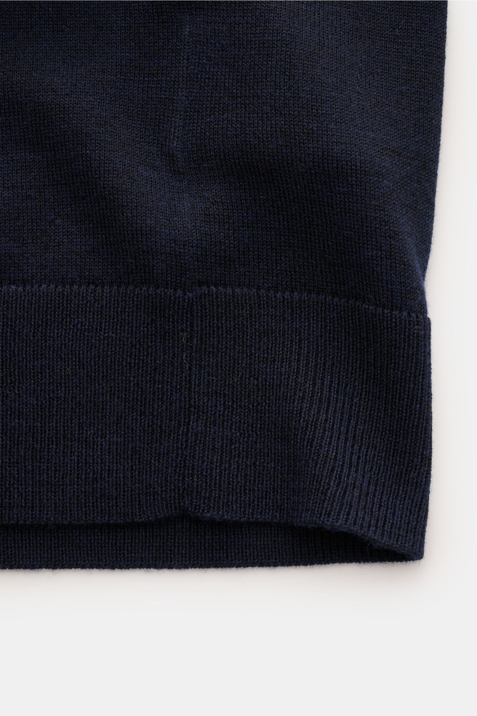 Nahaufnahme des unteren Saums des FTC Kurzarm-Strickpolo navy aus feinstem Cashmere-SeaCell-Mix, Slim Fit, mit weichem Griff und flexiblen Rippbündchen, fotografiert von vorne unten.