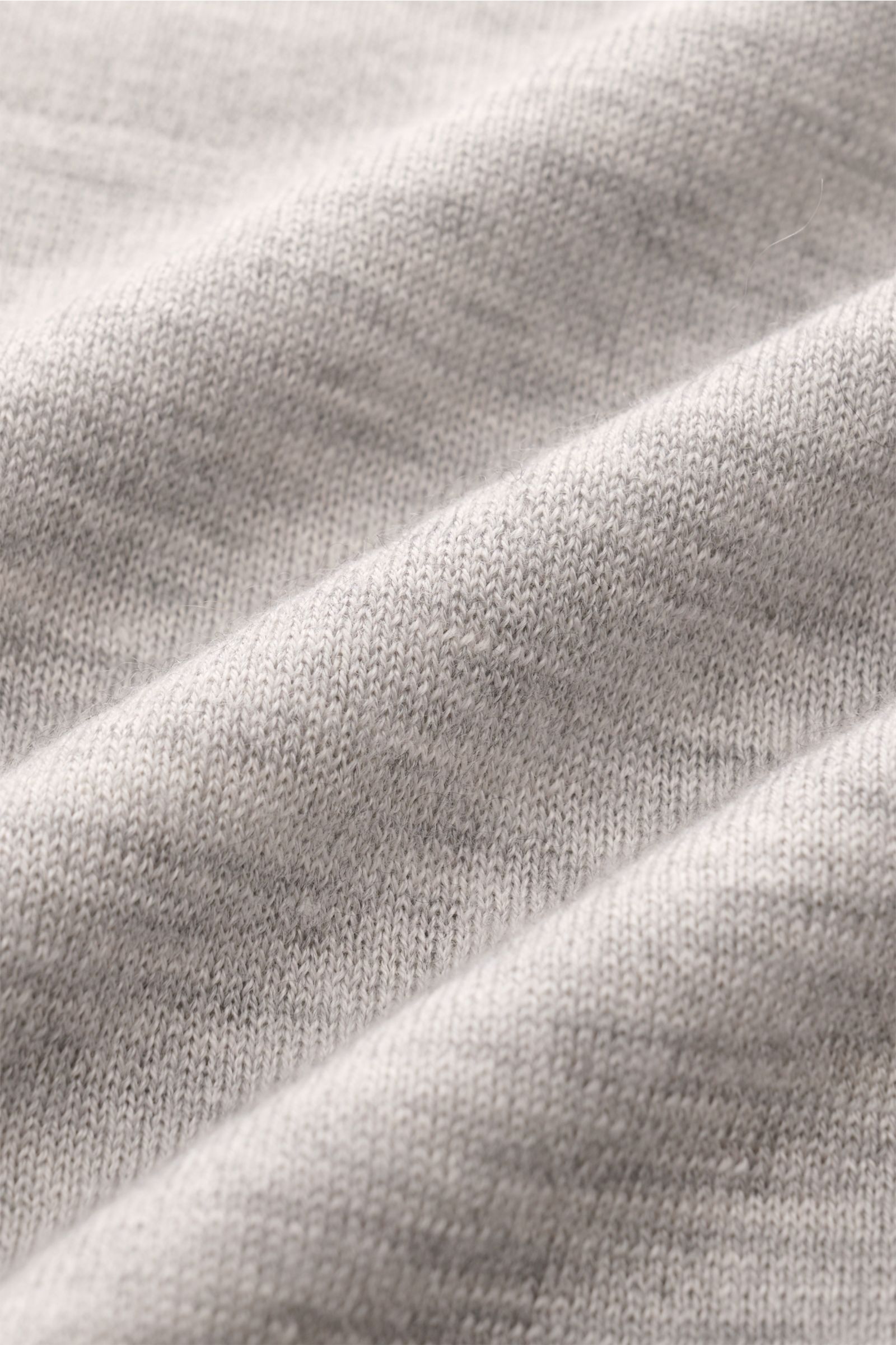 Nahaufnahme des feinen Strickbilds eines grau melierten FTC Kurzarm-Strickpolo aus Cashmere-SeaCell-Mix, nachhaltig produziert.