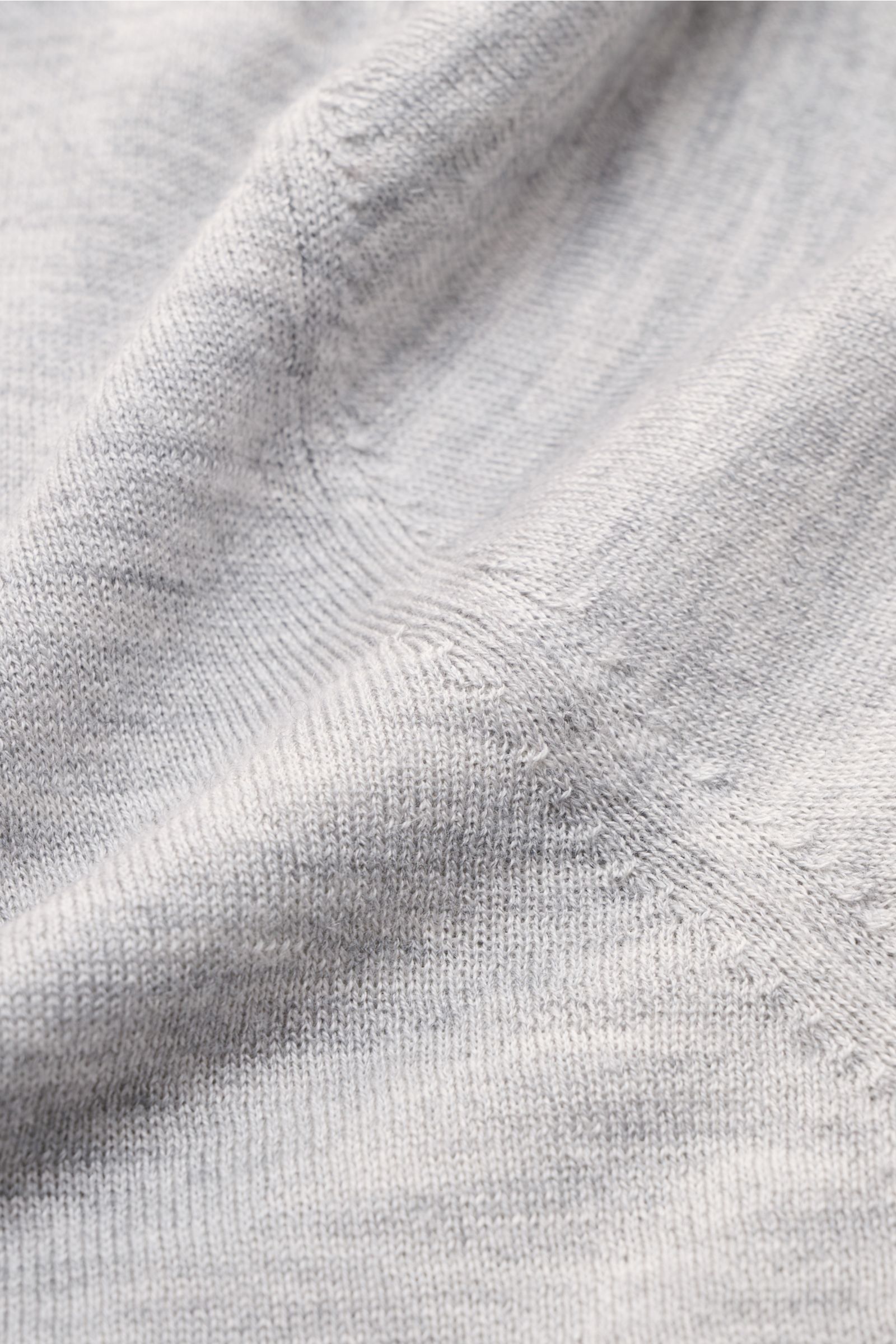 Nahaufnahme aus schräger Perspektive eines graumelierten FTC Kurzarm-Rundhalspullover aus nachhaltigem Cashmere-SeaCell-Mix mit feinem Strickbild.