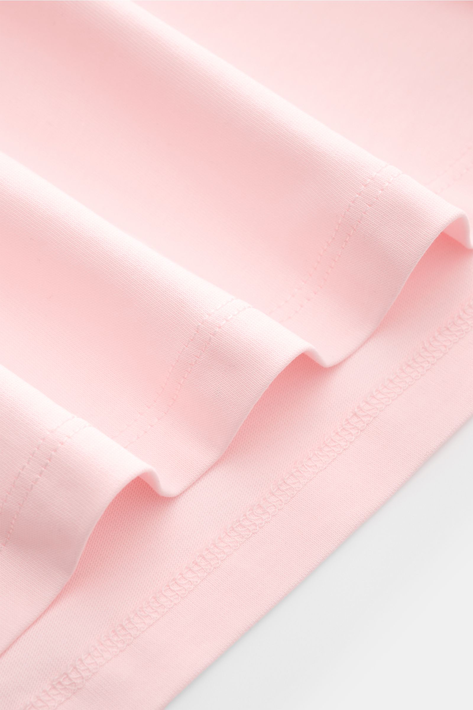 Nahaufnahme des Saums vom Kiefermann Rundhals T-Shirt 'Matello' rosé, körpernah geschnitten, Jersey aus Baumwolle, weicher, glatter Griff, dezenter Logodruck am Saum.