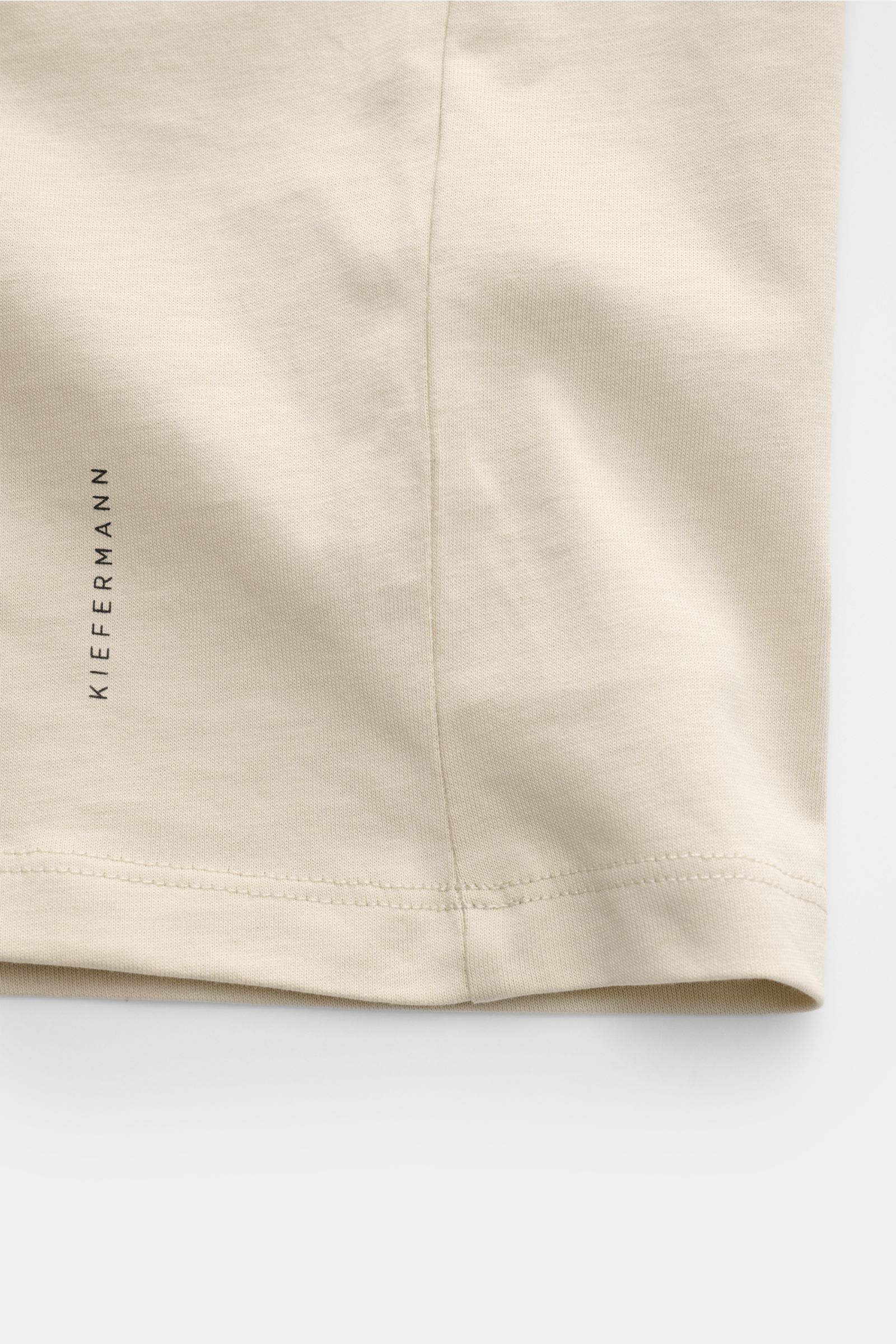 Kiefermann Rundhals T-Shirt 'Matello' sand, Detailaufnahme Saum mit dezentem Logodruck, Jersey aus Baumwolle, weicher, glatter Griff.