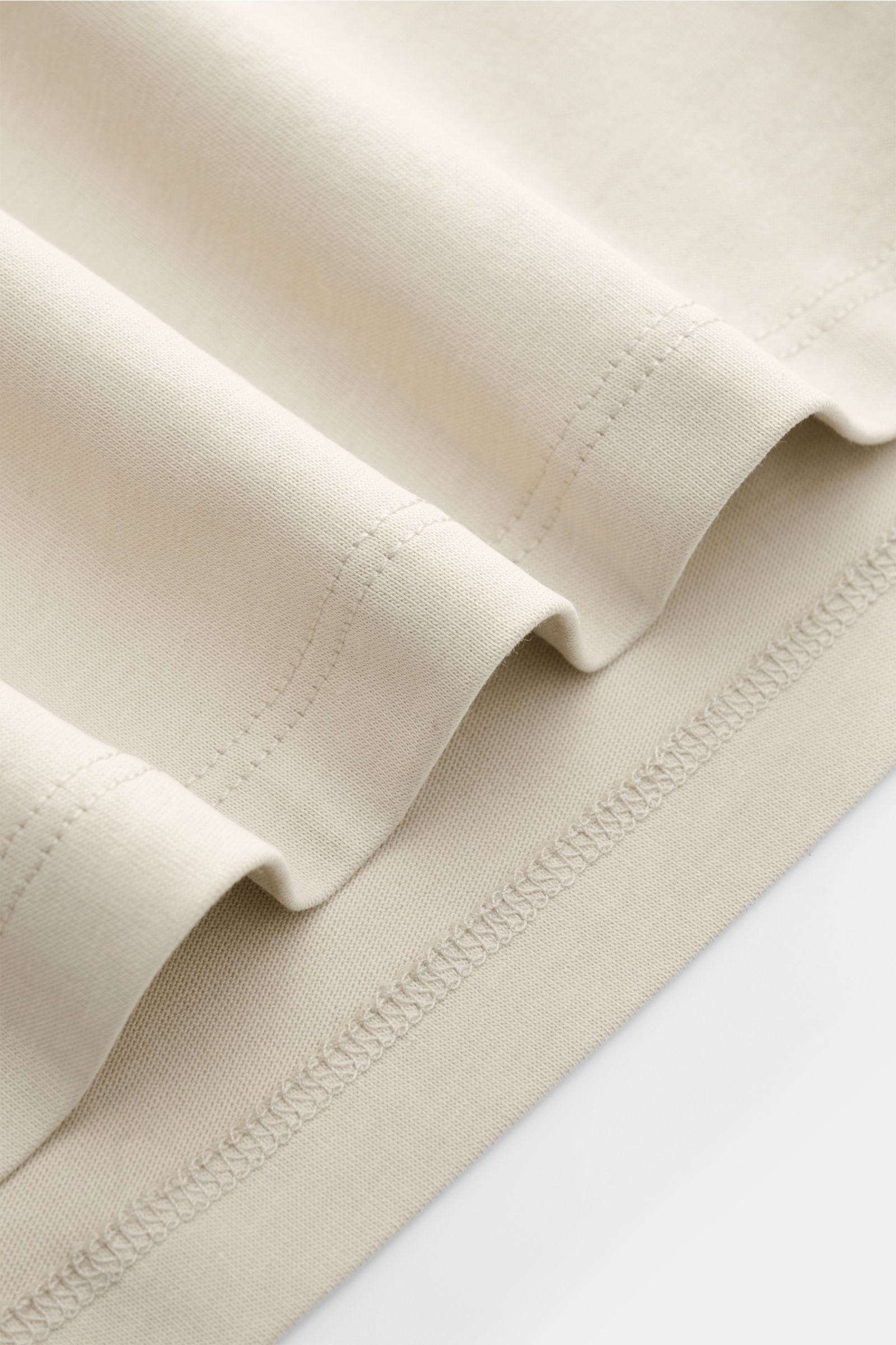 Nahaufnahme des Saums und der feinen Nähte des Kiefermann Rundhals T-Shirts 'Matello' sand aus weichem Baumwoll-Jersey, Extra Slim Fit, dezenter Logodruck, glatter Griff.