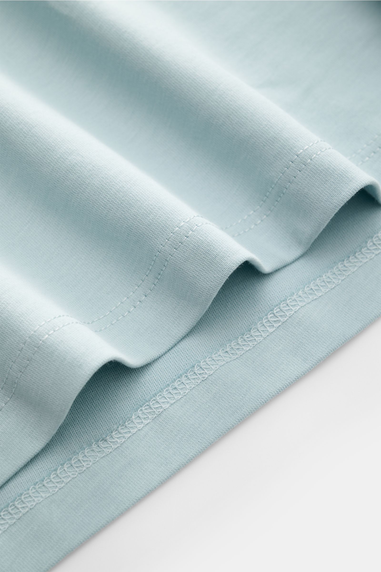 Nahaufnahme vom Saum des Kiefermann Rundhals T-Shirts 'Matello' hellblau aus weichem Baumwoll-Jersey mit extra Slim Fit und Logodruck.