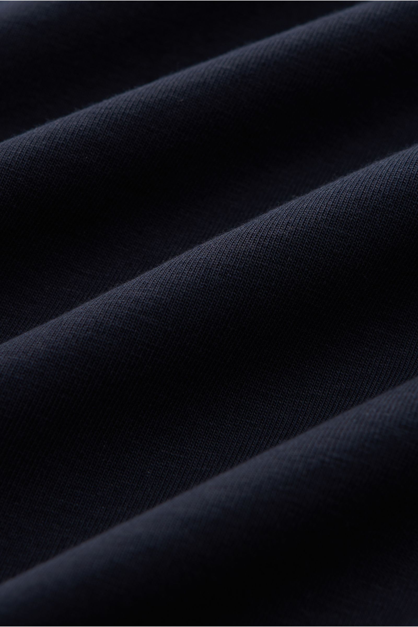 Close-up image of dark navy fabric showing texture and folds, highlighting the Kiefermann Crew neck T-shirt 'Lehon' dark navy made of soft cotton, elasticated fabric, soft feel, extra slim fit, and crew neck, photographed from a close front angle.
