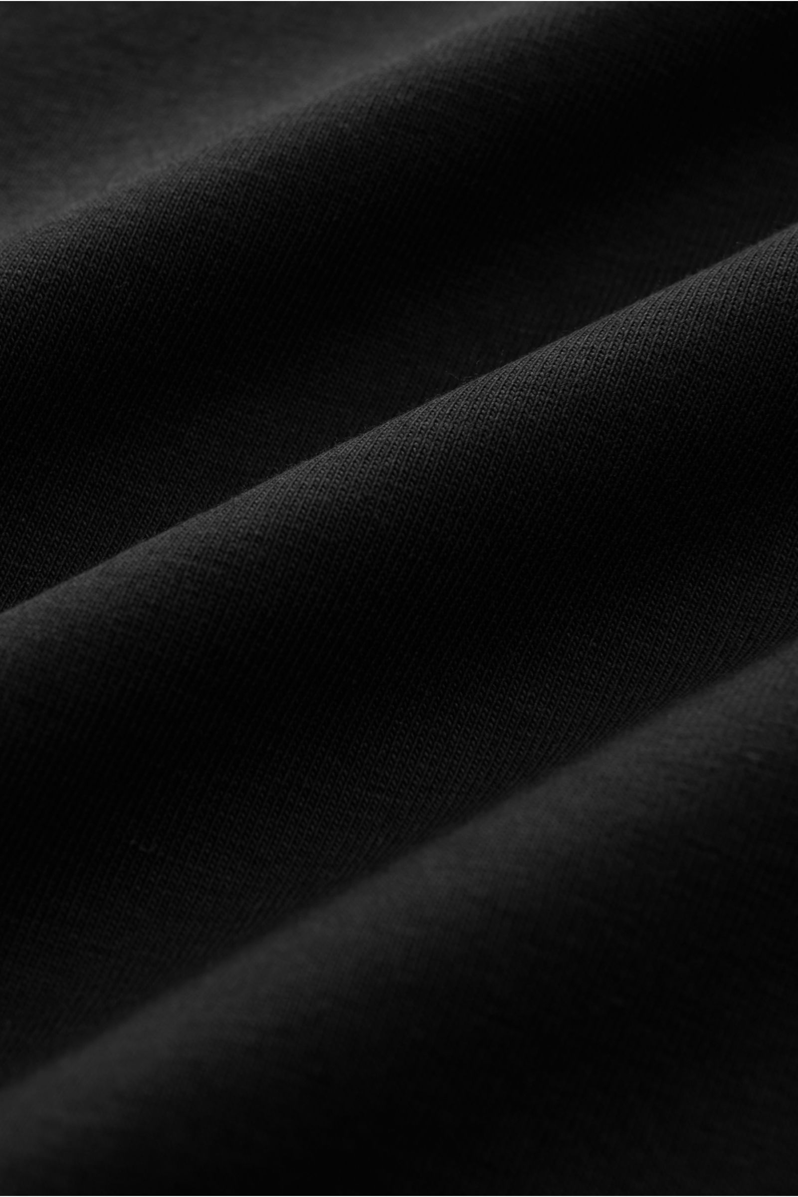 Close-up shot of the soft black fabric of the Kiefermann Crew neck T-shirt 'Lehon' black, showing texture and folds. Features: Soft cotton, Elasticated fabric, Soft feel, Extra slim fit, Crew neck.