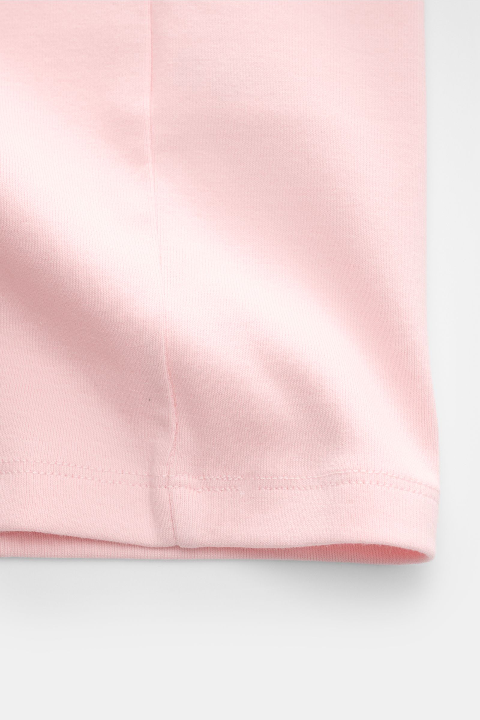 Nahaufnahme des Saum-Bereichs vom Kiefermann Rundhals-T-Shirt 'Arndell' rosé aus elastischer Baumwolle mit weichem Griff, Regular Fit und Rundhalsausschnitt, fotografiert von unten.