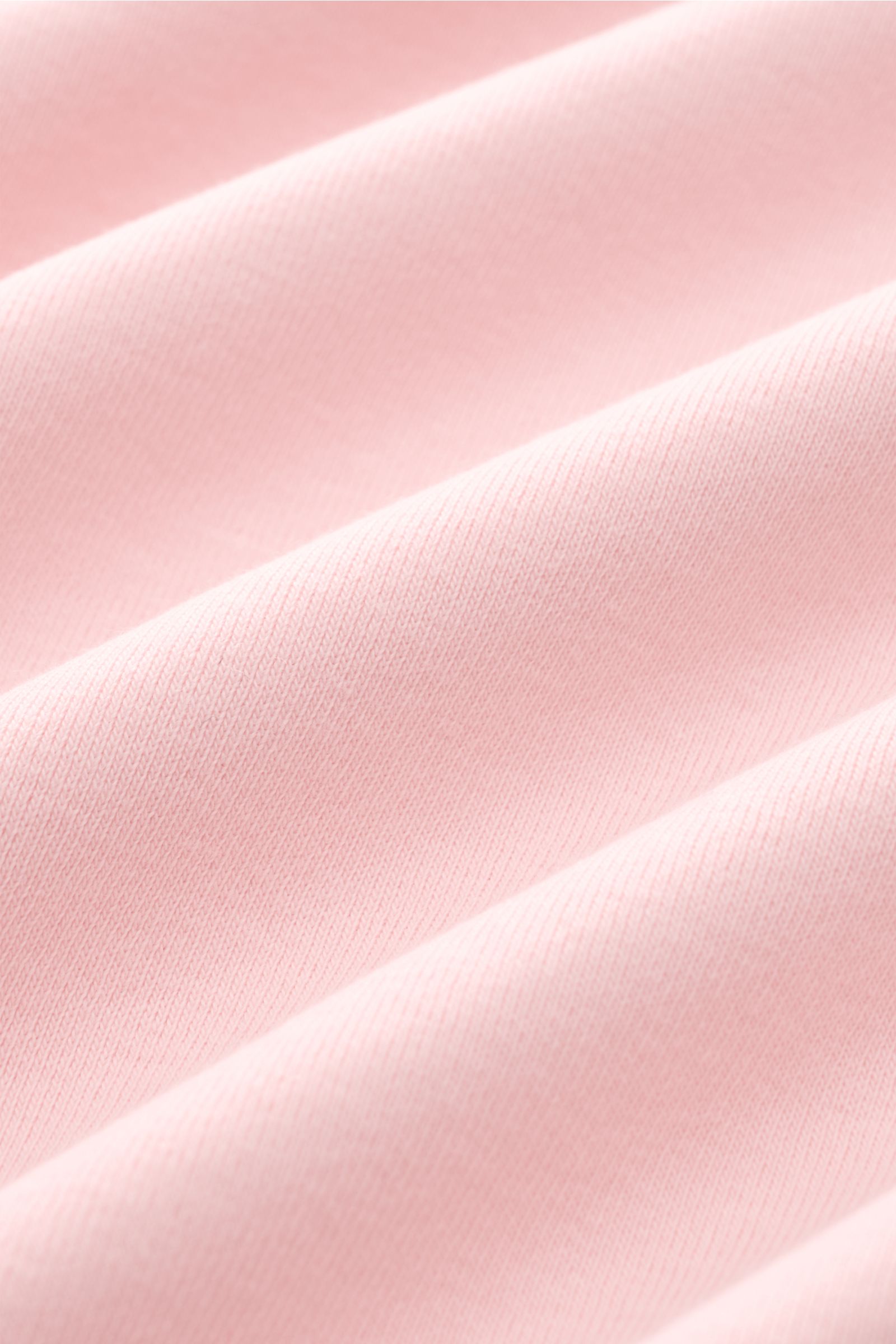 Nahaufnahme des weichen, elastischen Baumwollstoffs in rosé des Kiefermann Rundhals-T-Shirt 'Arndell', fotografiert aus schräger Perspektive. Vielseitiges Basic mit Regular Fit und Rundhalsausschnitt, ideal für warme Frühling- und Sommertage.
