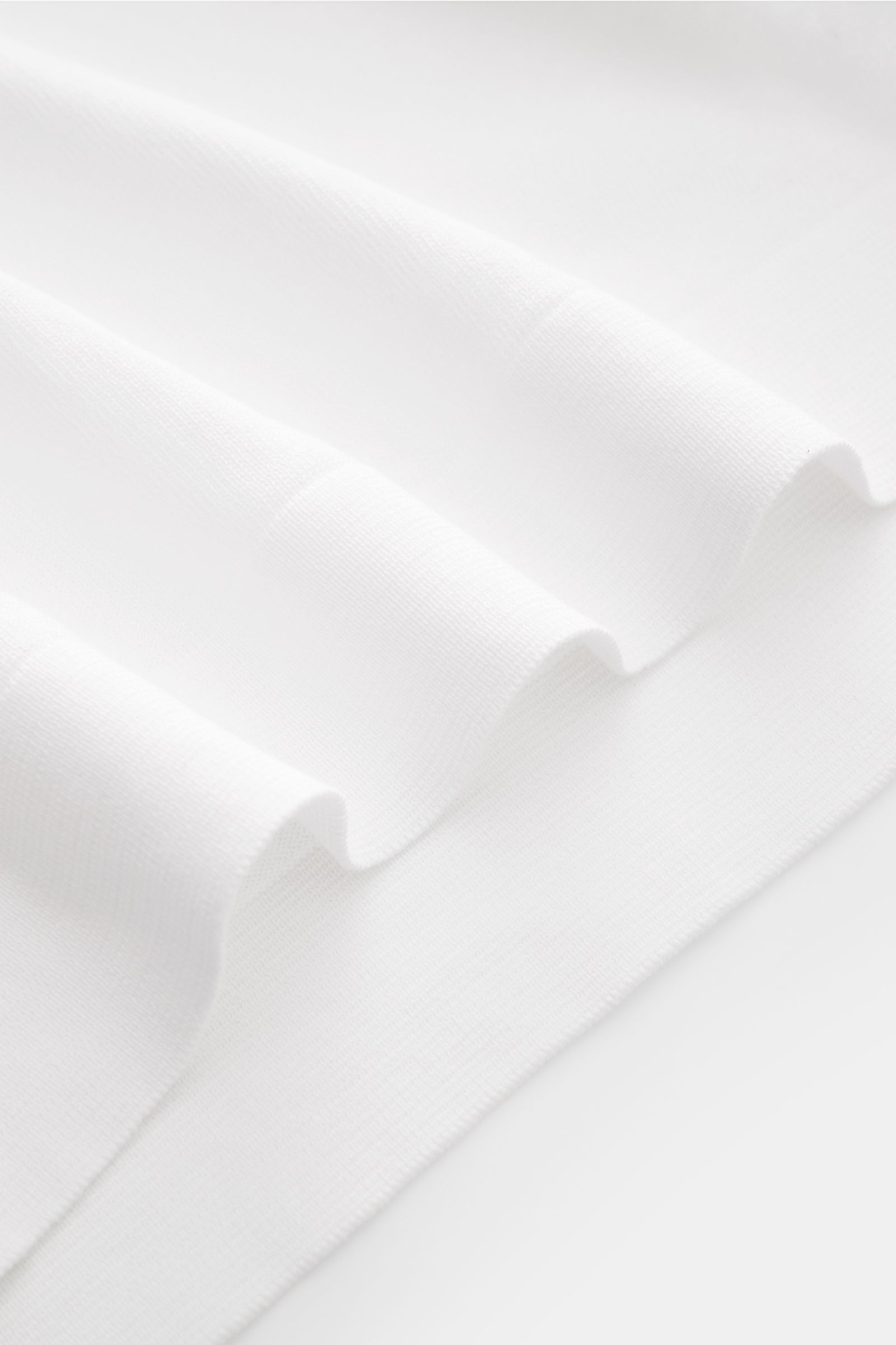 White fine knit fabric detail of the Filippo de Laurentiis Feinstrick-Kurzarmpullover weiß, photographed close-up from a side angle. Sommerliche Knitwear: Mit diesem kurzärmeligen Feinstrickpullover aus reiner Baumwolle präsentiert FILIPPO DE LAURENTIIS e