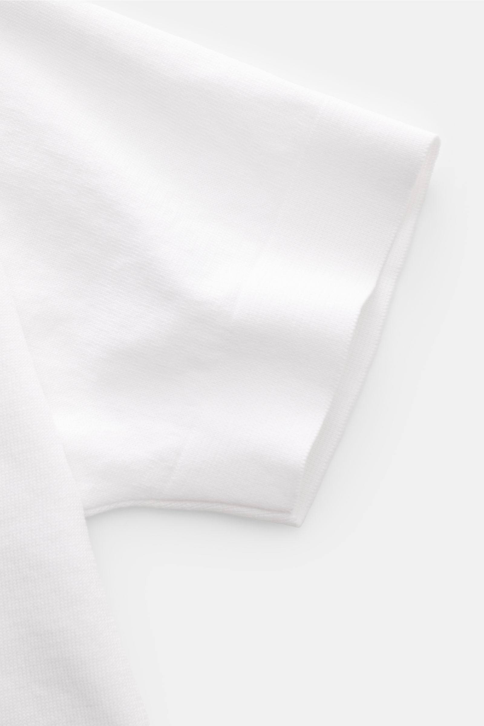 Close-up of the short sleeve of the Filippo de Laurentiis Feinstrick-Kurzarmpullover weiß, photographed from above, showing fine knit cotton fabric with soft touch, slim fit, round neckline, comfortable cuffs, and side slits. Sommerliche Knitwear: Mit die