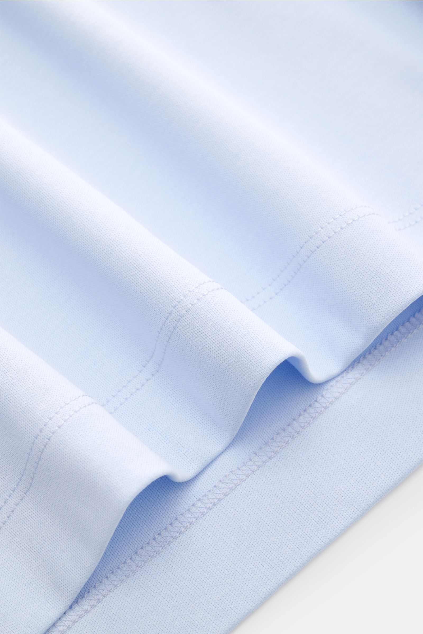 Close-up side view of the hem of the Aurélien Rundhals-T-Shirt hellblau, showcasing jersey made from Egyptian cotton, soft smooth touch, slim fit, round neckline, short side slits, and subtle logo stitching on the back.