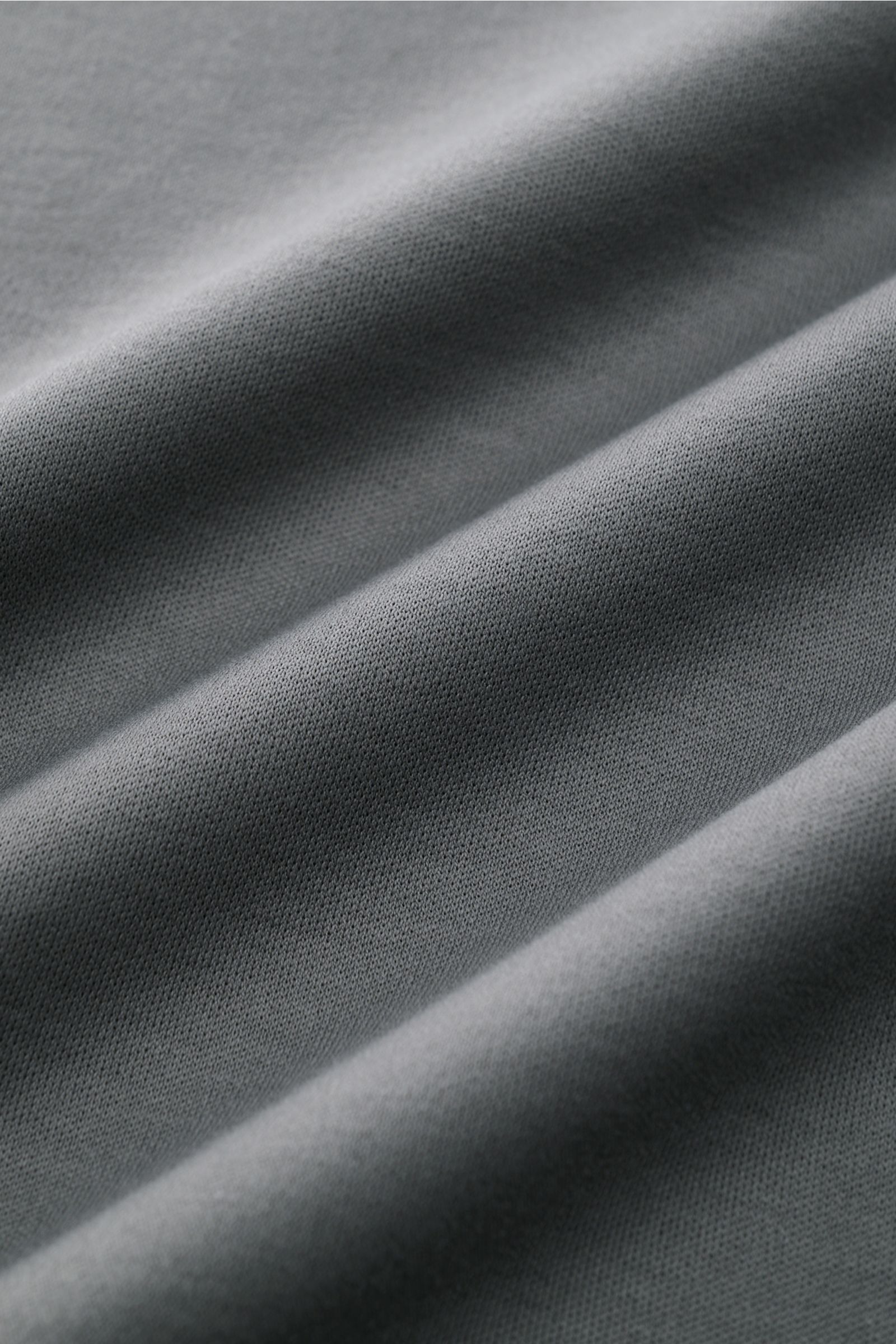 Nahaufnahme des dunkelgrauen Jersey-Stoffs des Aurélien Rundhals-T-Shirt, Slim Fit, ägyptische Baumwolle, glatter Griff, kurze Saumschlitze, dezentes Logo-Stitching.