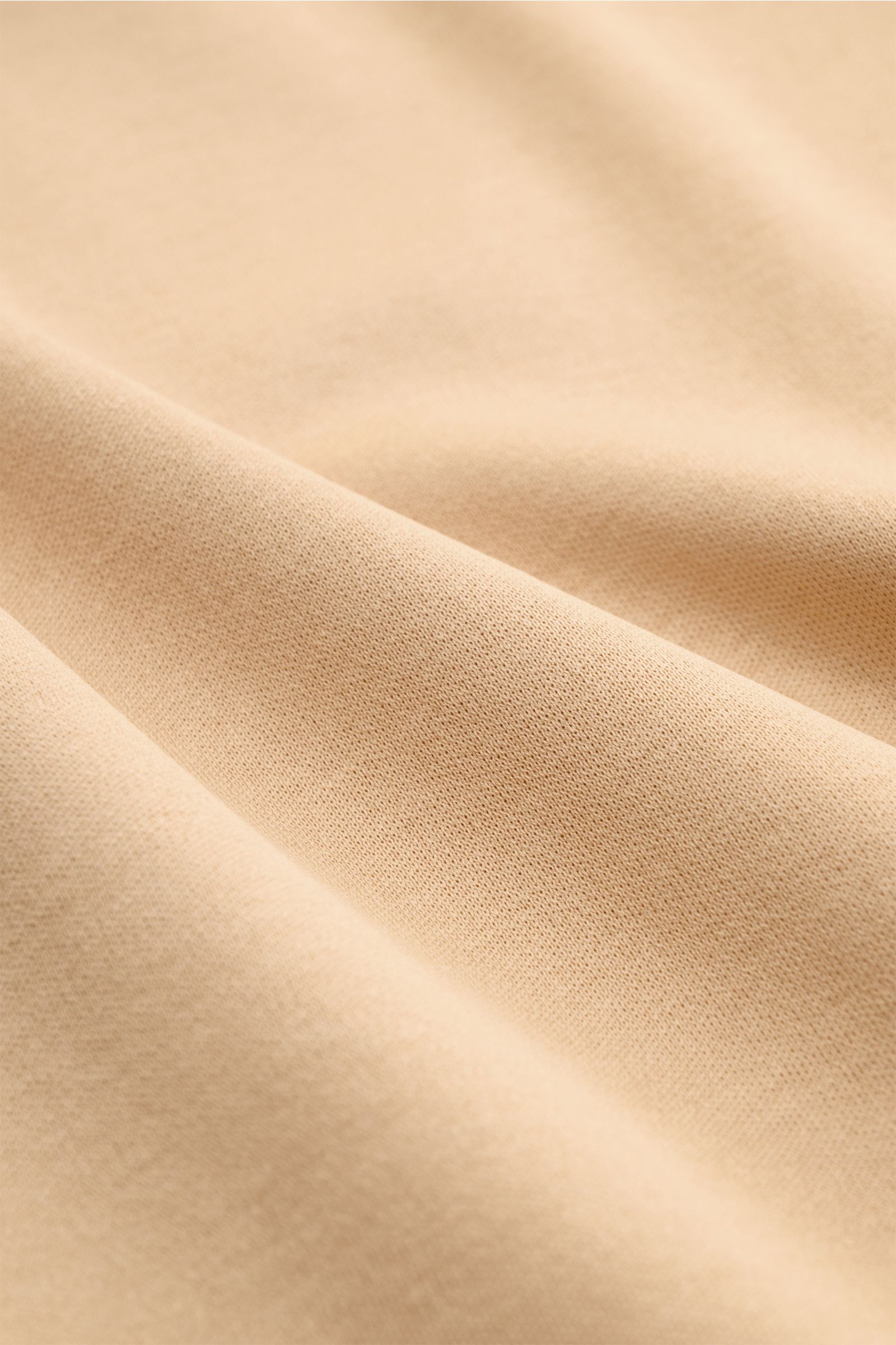 Nahaufnahme des weichen, beigen Aurélien Rundhals-T-Shirts aus reiner Baumwolle mit Slim Fit und kurzen Saumschlitzen.