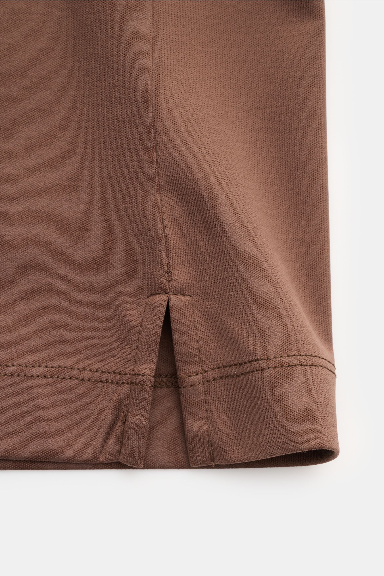 Nahaufnahme des unteren Saums mit kurzen Saumschlitzen des braunen Aurélien Rundhals-T-Shirts aus reiner Baumwolle, Slim Fit, weicher Griff, klare, zeitlose Frühling- und Sommer-Basics.