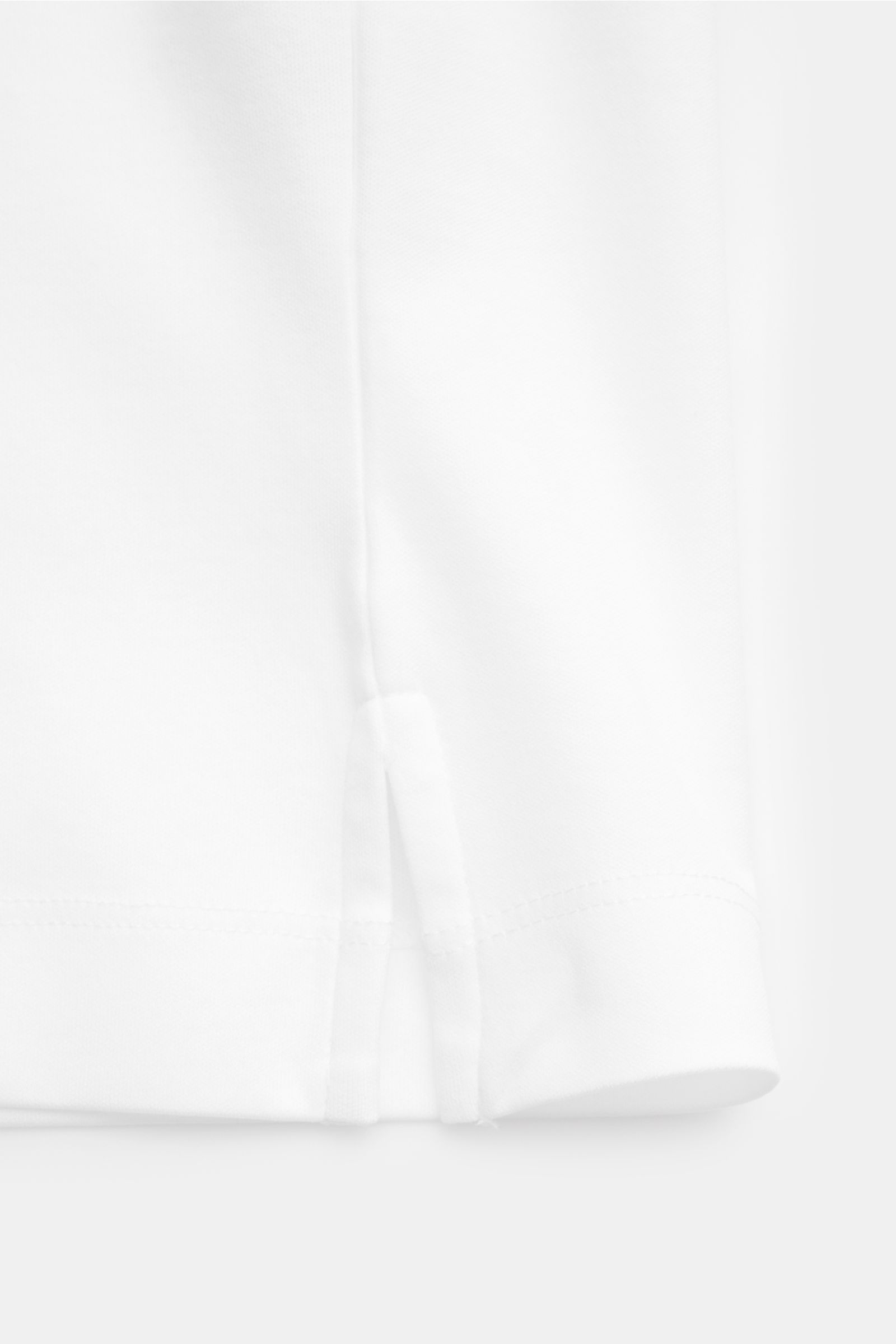 Nahaufnahme des unteren Saums mit kurzen Saumschlitzen des weißen Aurélien Rundhals-T-Shirts aus weicher, reiner Baumwolle im Slim Fit.