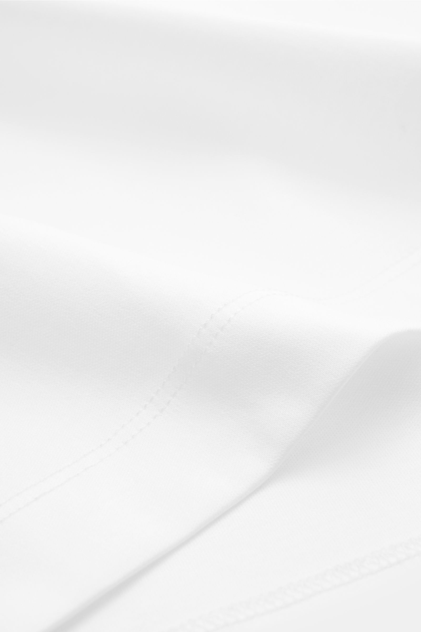 Aurélien Rundhals-T-Shirt weiß aus reiner Baumwolle, Slim Fit, weicher Griff, Rundhalsausschnitt, kurze Saumschlitze, Nahaufnahme Stoffstruktur.