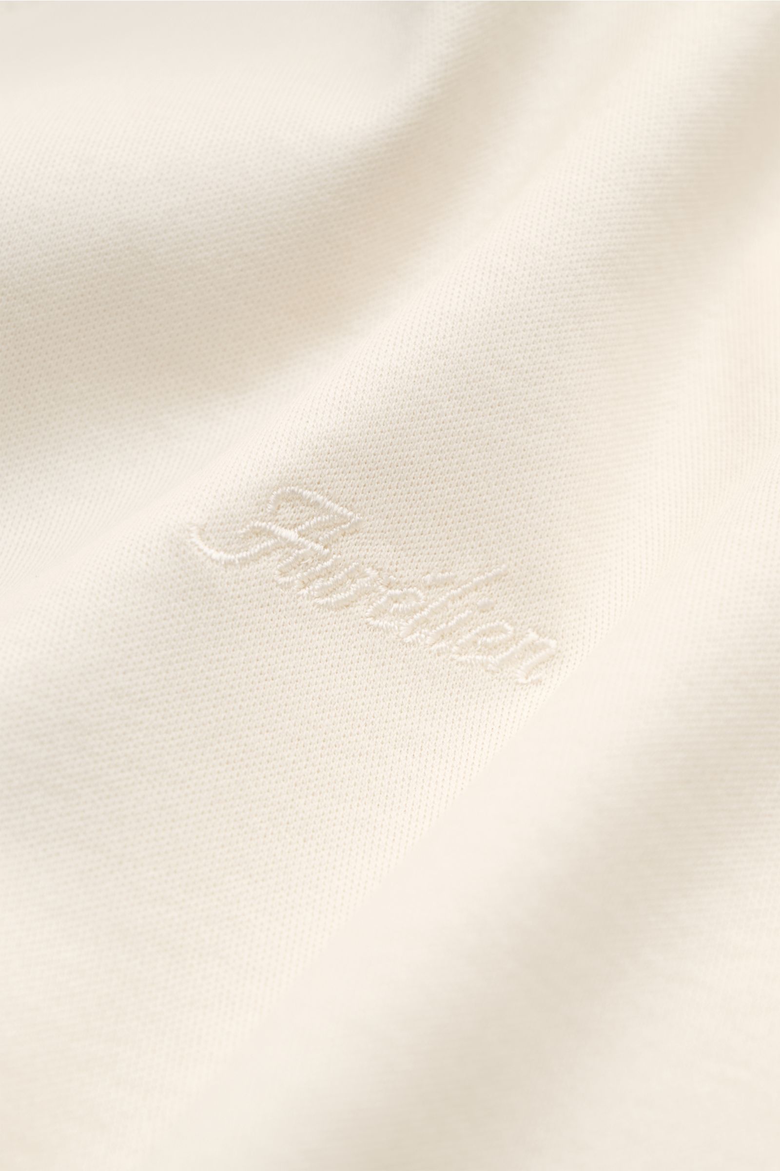 Nahaufnahme des Aurélien Rundhals-T-Shirt creme aus weicher, reiner Baumwolle mit tonalem Logo-Stitching und feiner Struktur.