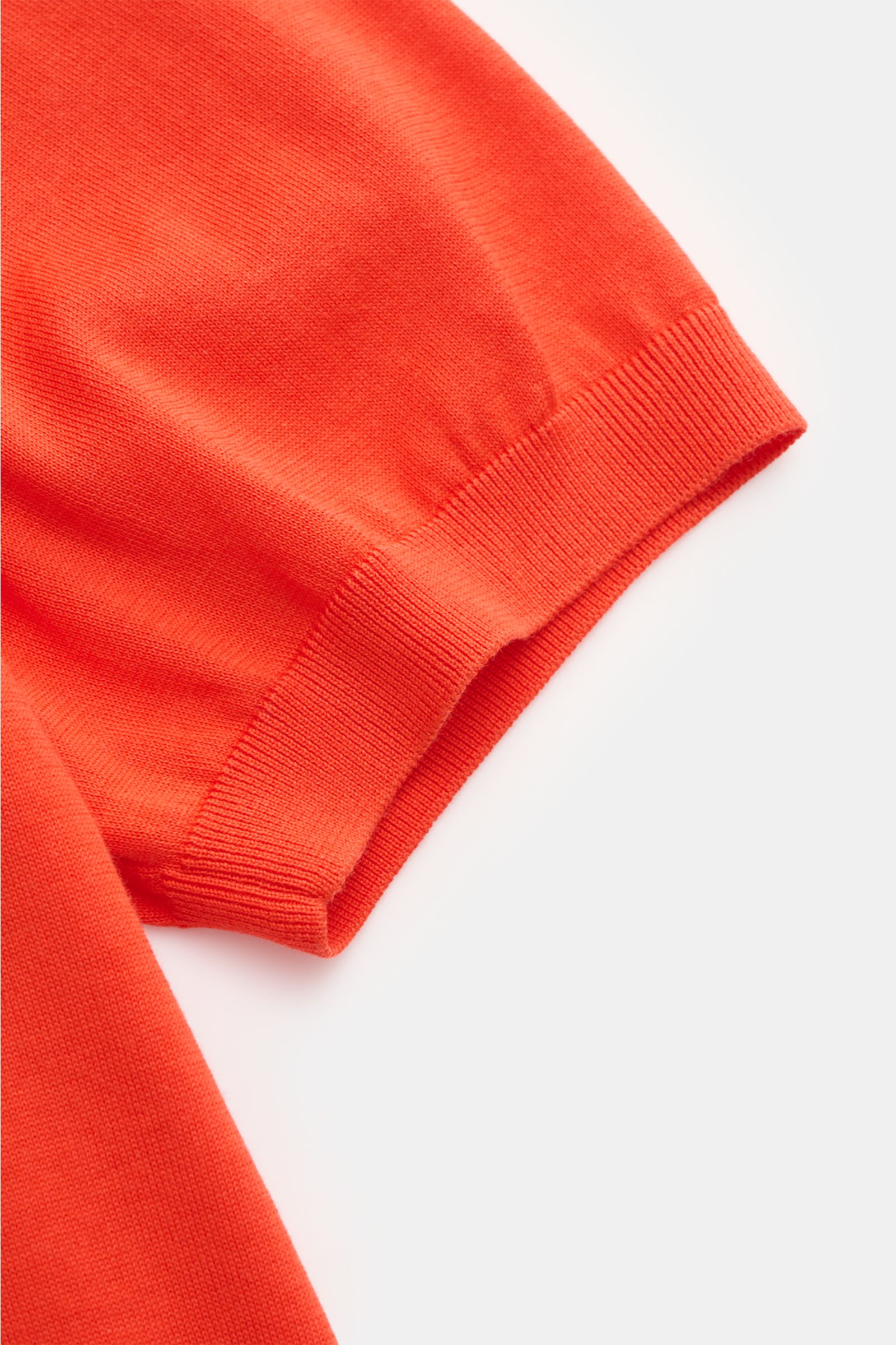 Nahaufnahme des roten Drumohr Kurzarmpullovers, fotografiert von oben, zeigt feines Strickbild, elastische Rippbündchen, weich und Slim Fit, aus reiner Baumwolle, hergestellt in Italien.