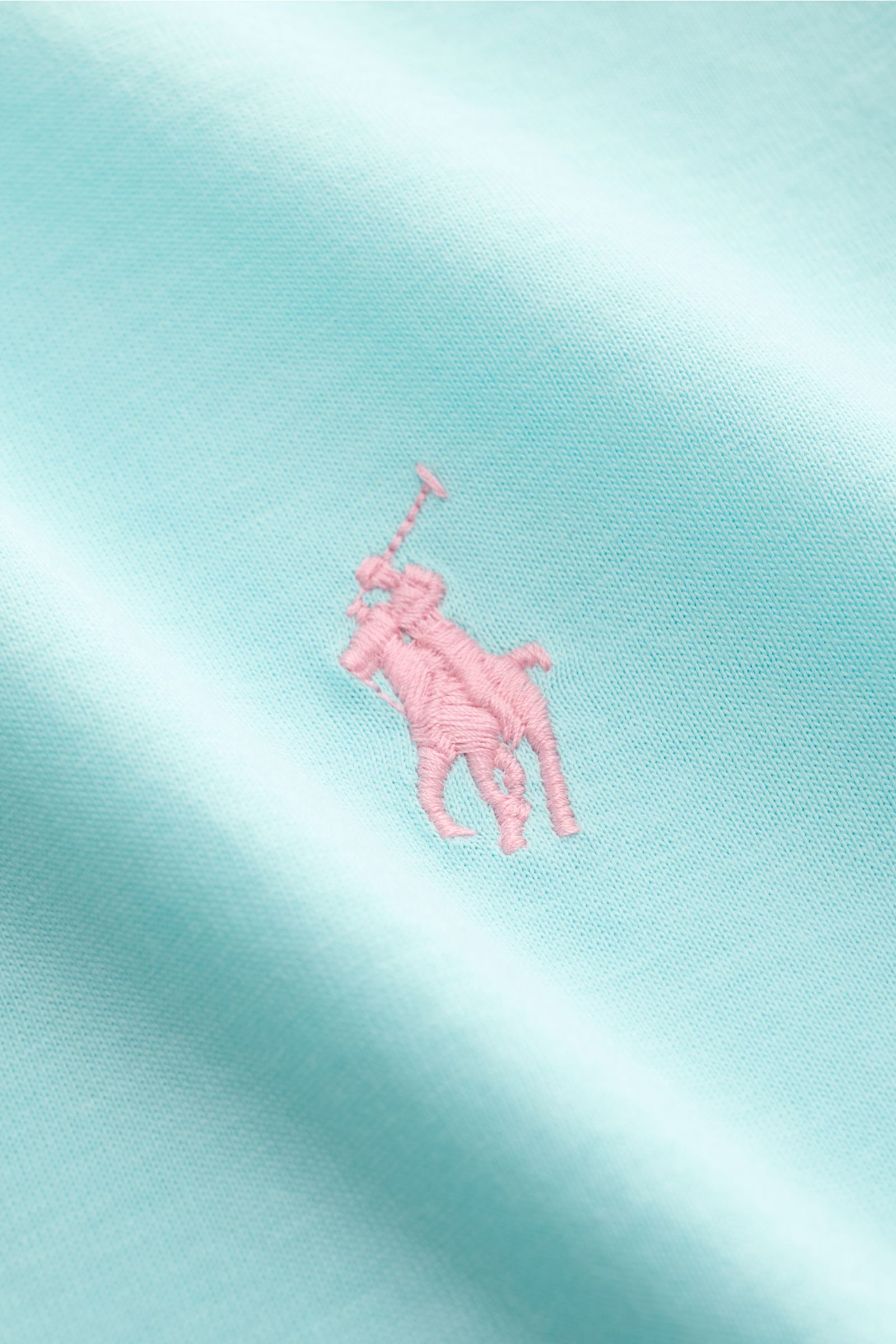 Nahaufnahme des Polo Ralph Lauren Rundhals-T-Shirt türkis, weiches Baumwoll-Jersey mit rosa Logo-Stitching, schmale Silhouette sichtbar.