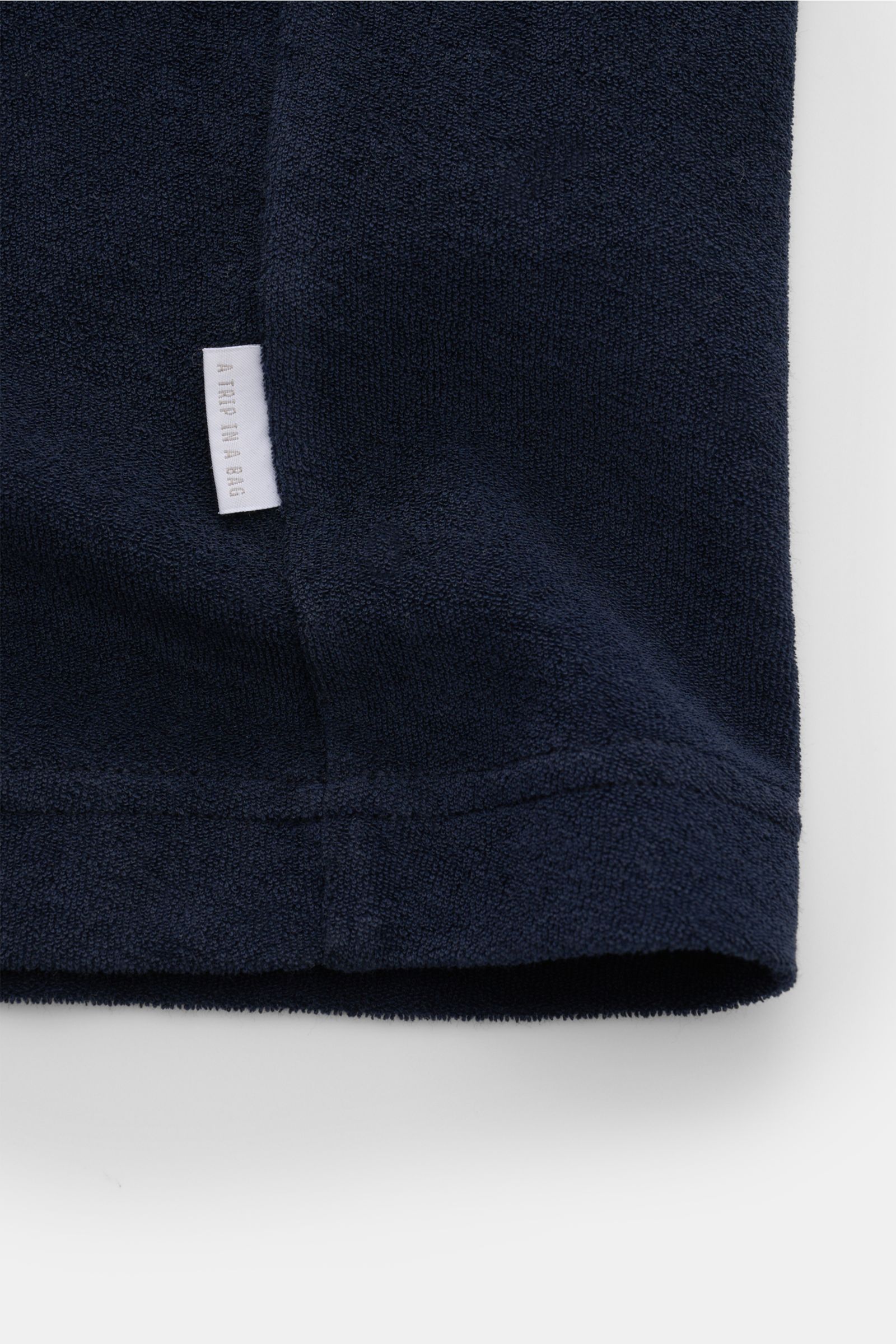 Close-up of the hem and side seam of the 04651/ A trip in a bag Terry T-shirt 'Terry Tee' navy, showing soft terrycloth fabric and small woven label, photographed from a front low angle.

The clean T-shirt 'Terry Tee' by 04651/ A TRIP IN A BAG is made 