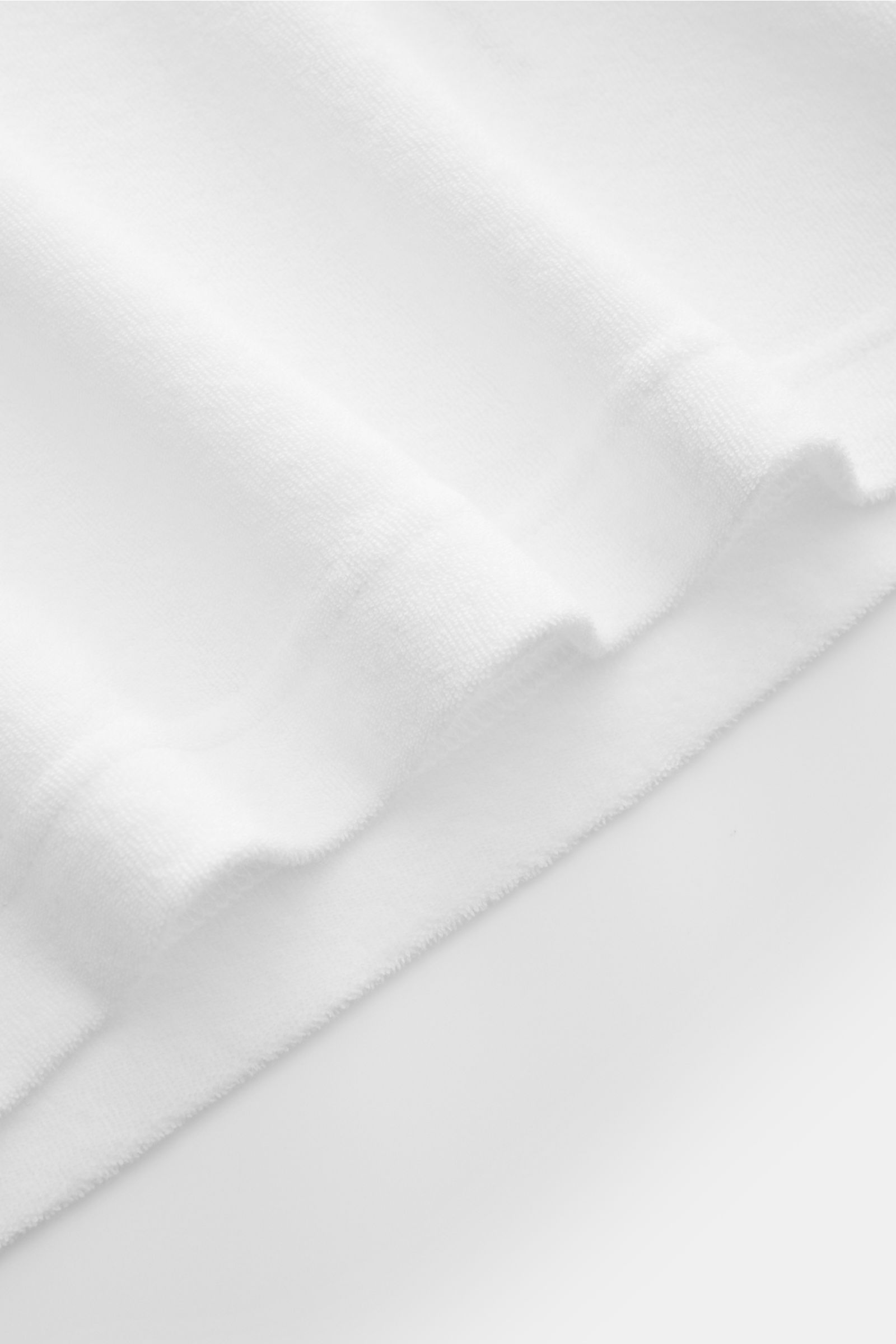 Close-up top view of the soft terrycloth fabric of the 04651/ A trip in a bag Terry T-shirt 'Terry Tee' white, showing texture and folds.

The clean T-shirt 'Terry Tee' by 04651/ A TRIP IN A BAG is made of soft terry in pure cotton fabric and is the pe