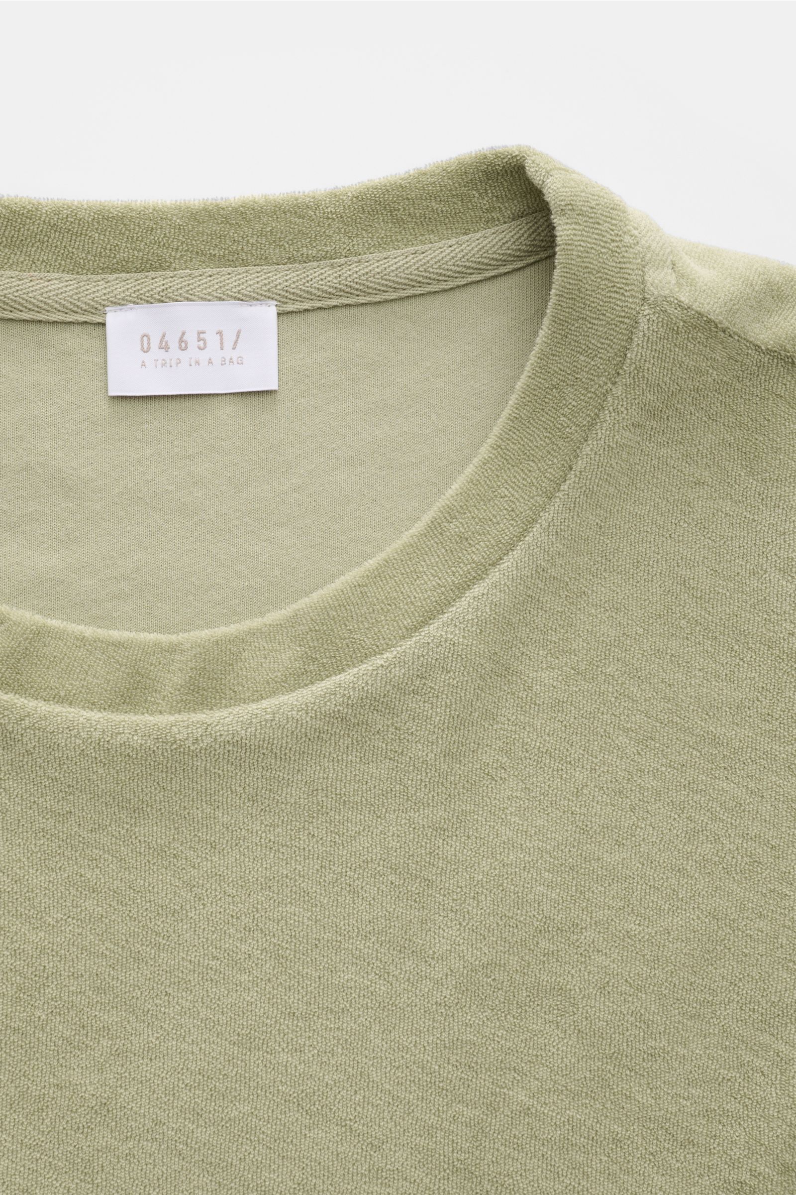 Close-up front view of the 04651/ A trip in a bag Terry T-shirt 'Terry Tee' sage, showing soft terrycloth crew neck and label.

The clean T-shirt 'Terry Tee' by 04651/ A TRIP IN A BAG is made of soft terry in pure cotton fabric and is the perfect every