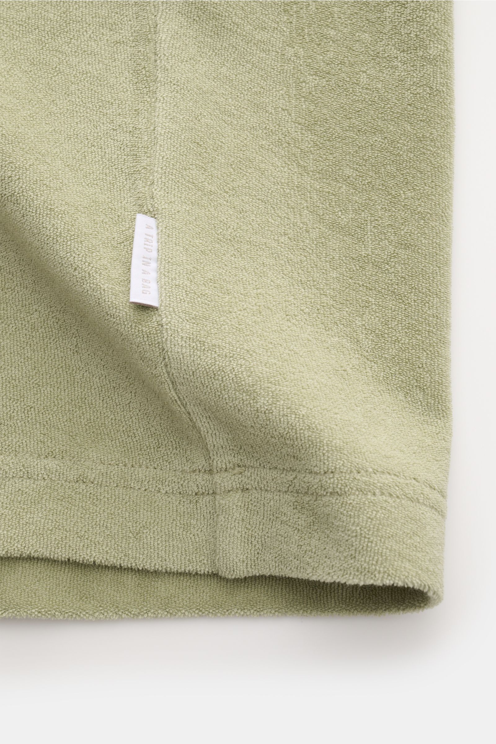 Close-up side view of the 04651/ A trip in a bag Terry T-shirt 'Terry Tee' sage showing soft terrycloth fabric, small woven label, and hem details.

The clean T-shirt 'Terry Tee' by 04651/ A TRIP IN A BAG is made of soft terry in pure cotton fabric and