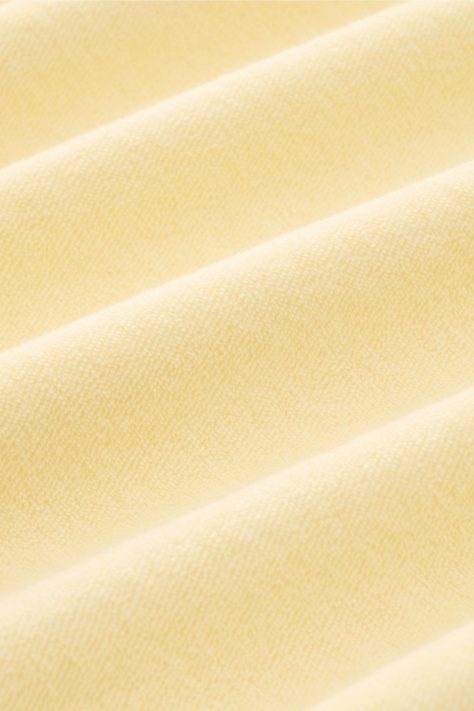 Nahaufnahme des weichen Frottee-Stoffs des 04651/ A trip in a bag Frottee T-Shirts 'Terry Tee' pastellgelb mit feiner Struktur.