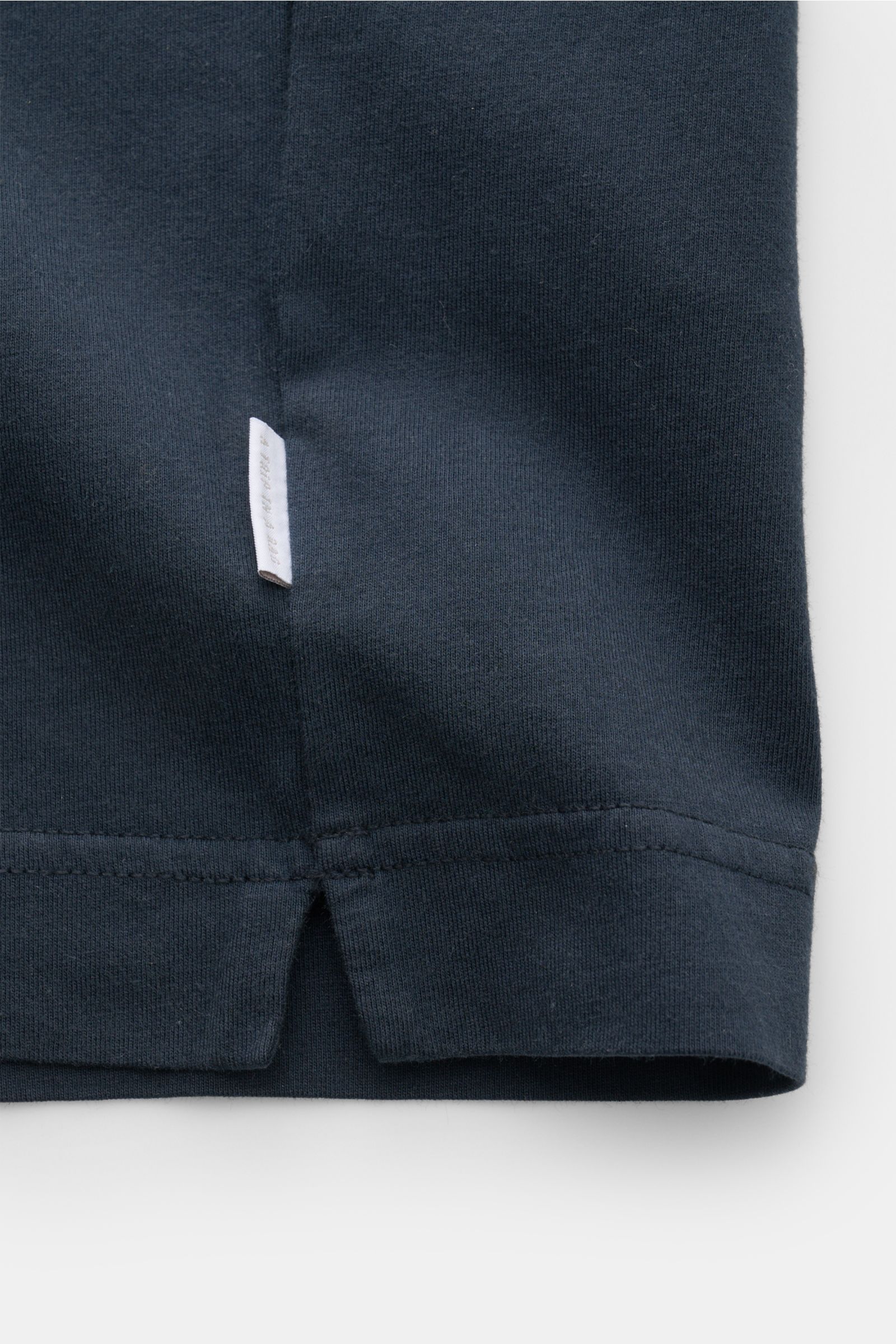 Nahaufnahme des unteren Saums des 04651/ A trip in a bag Rundhals-T-Shirts navy, Jersey aus reiner Baumwolle, weicher Griff, Regular Fit, Rundhalsausschnitt, kleines Weblabel und kurze Saumschlitze sichtbar.