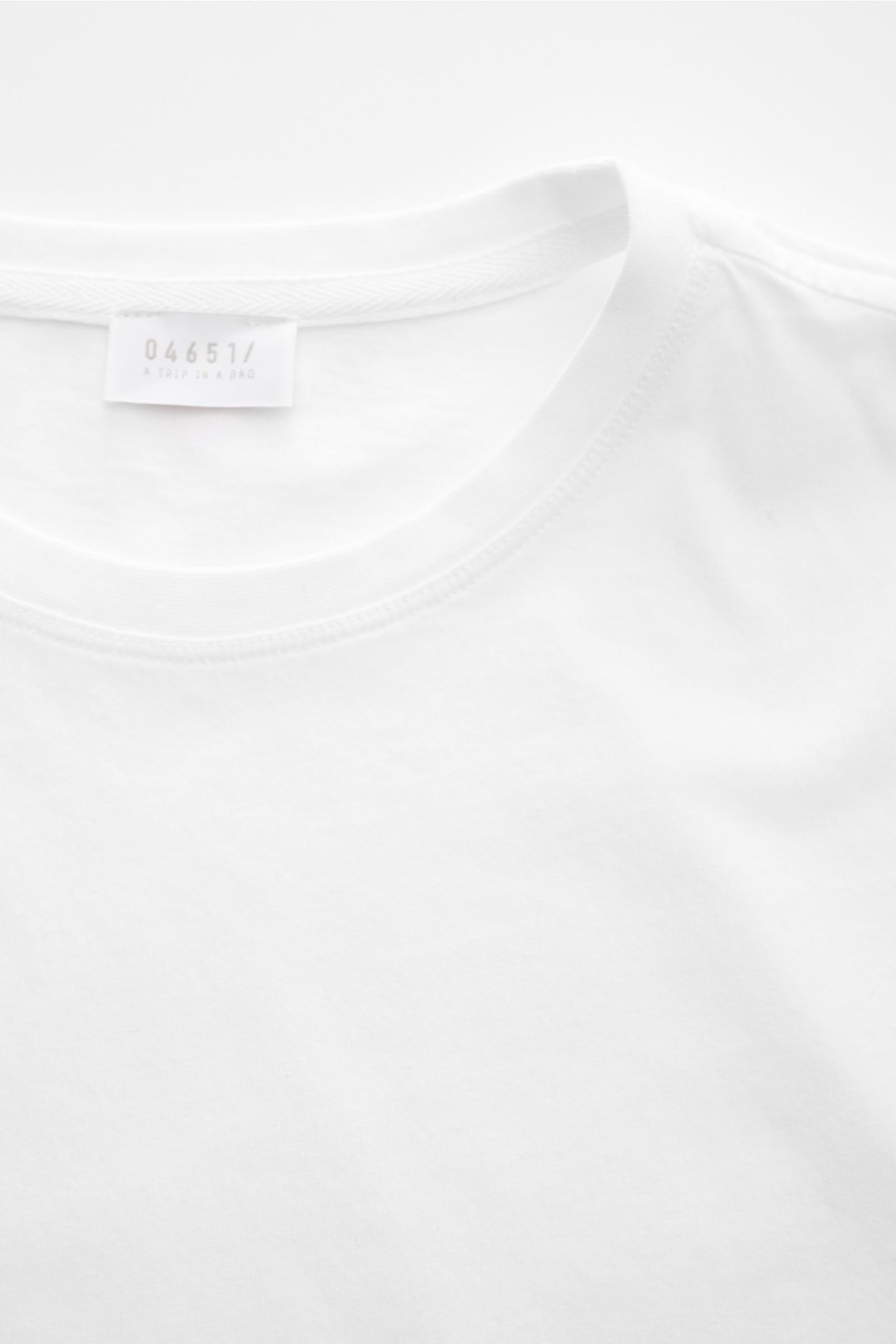 04651/ A trip in a bag Rundhals-T-Shirt weiß, Detailfoto von oben, Jersey aus reiner Baumwolle, weicher Griff, Regular Fit, Rundhalsausschnitt, kleines Weblabel, kurze Saumschlitze.