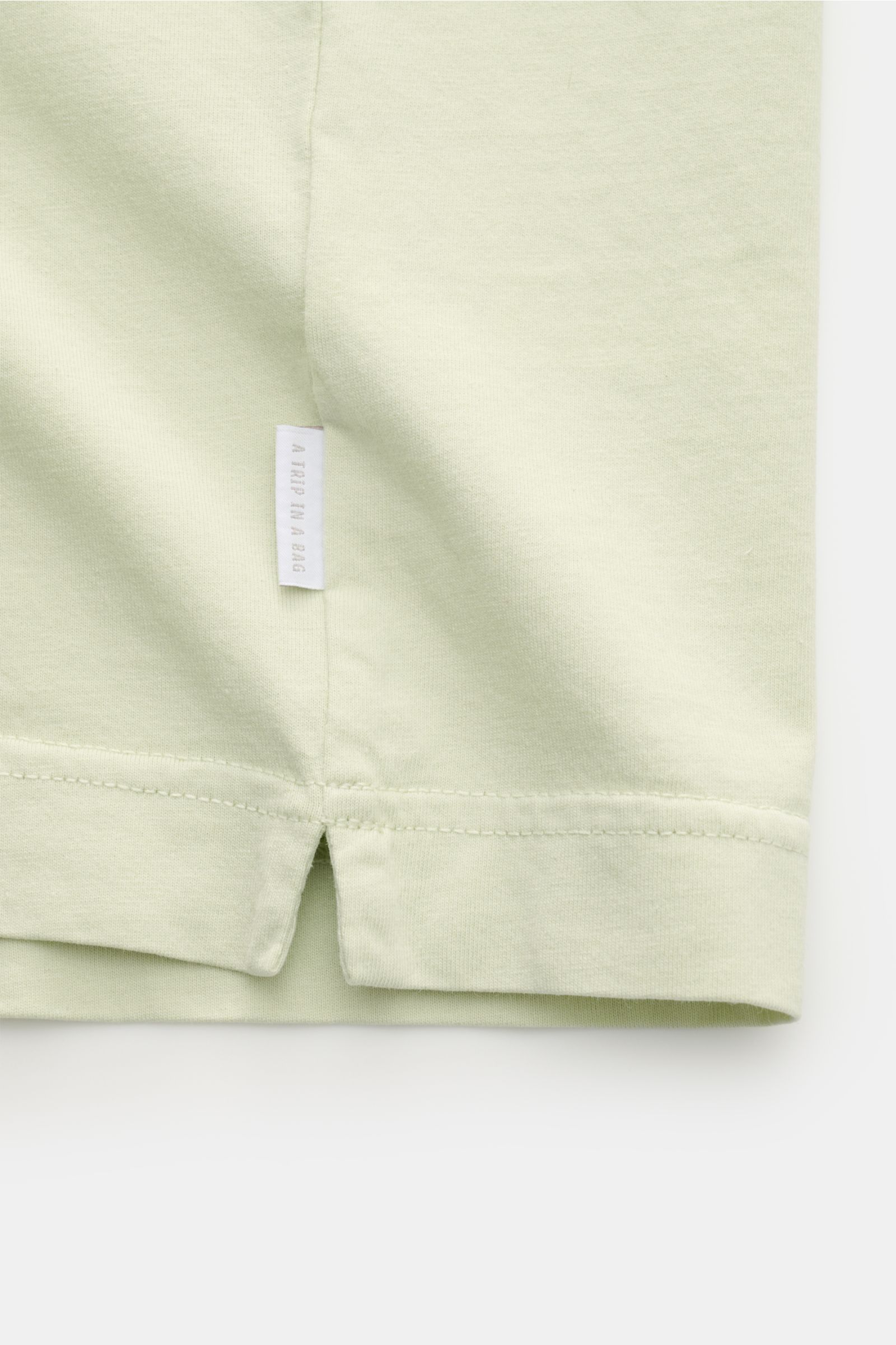 Nahaufnahme des Saumdetails mit kleinem Weblabel des 04651/ A trip in a bag Rundhals-T-Shirt pastellgrün, Jersey aus reiner Baumwolle, weicher Griff, Regular Fit, Rundhalsausschnitt.