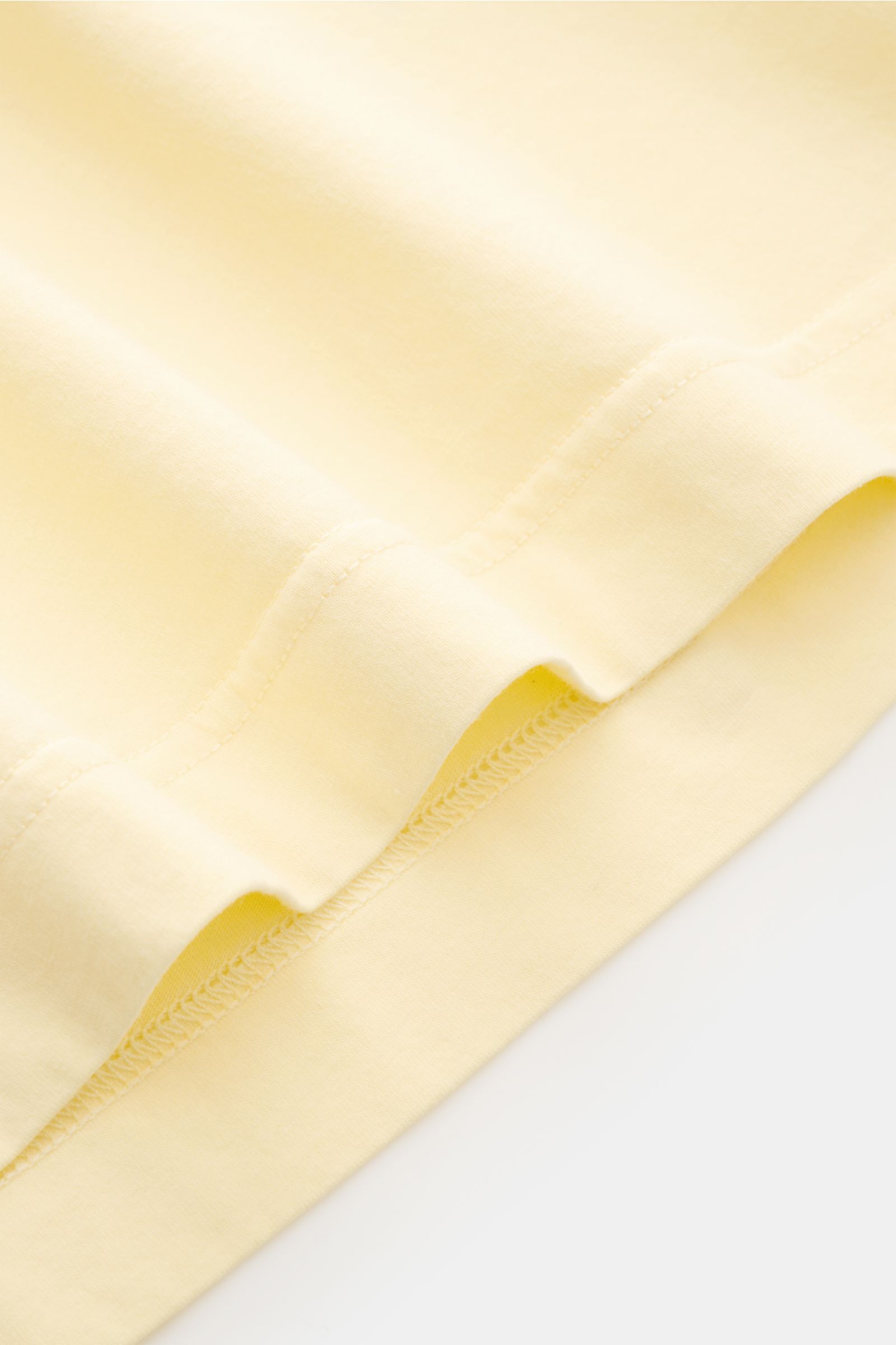 Nahaufnahme der Saumkante des 04651/ A trip in a bag Rundhals-T-Shirts pastellgelb, Jersey aus reiner Baumwolle, weicher Griff, Regular Fit, Rundhalsausschnitt, kleines Weblabel.