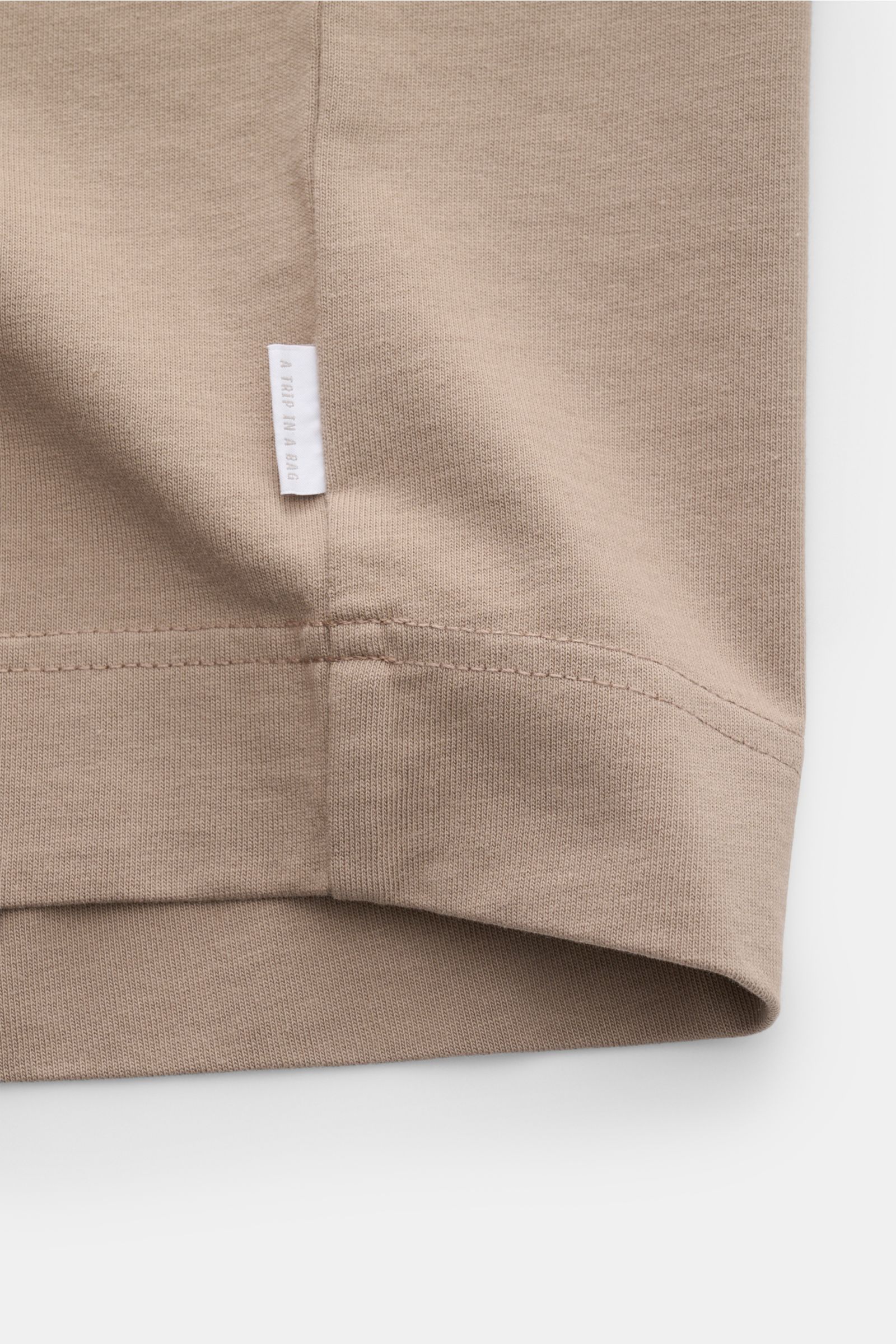 04651/ A trip in a bag Rundhals-T-Shirt taupe, Detailansicht Saum und kleines Weblabel, schwere Baumwolle, Regular Fit, Rundhalsausschnitt.