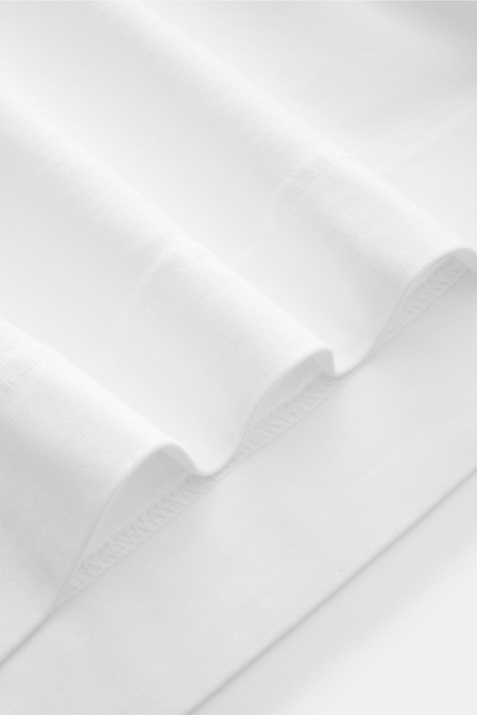 Nahaufnahme des Saum und Stoffstruktur des 04651/ A trip in a bag Rundhals-T-Shirt weiß, gefertigt aus schwerem Baumwoll-Jersey mit kleinem Weblabel.