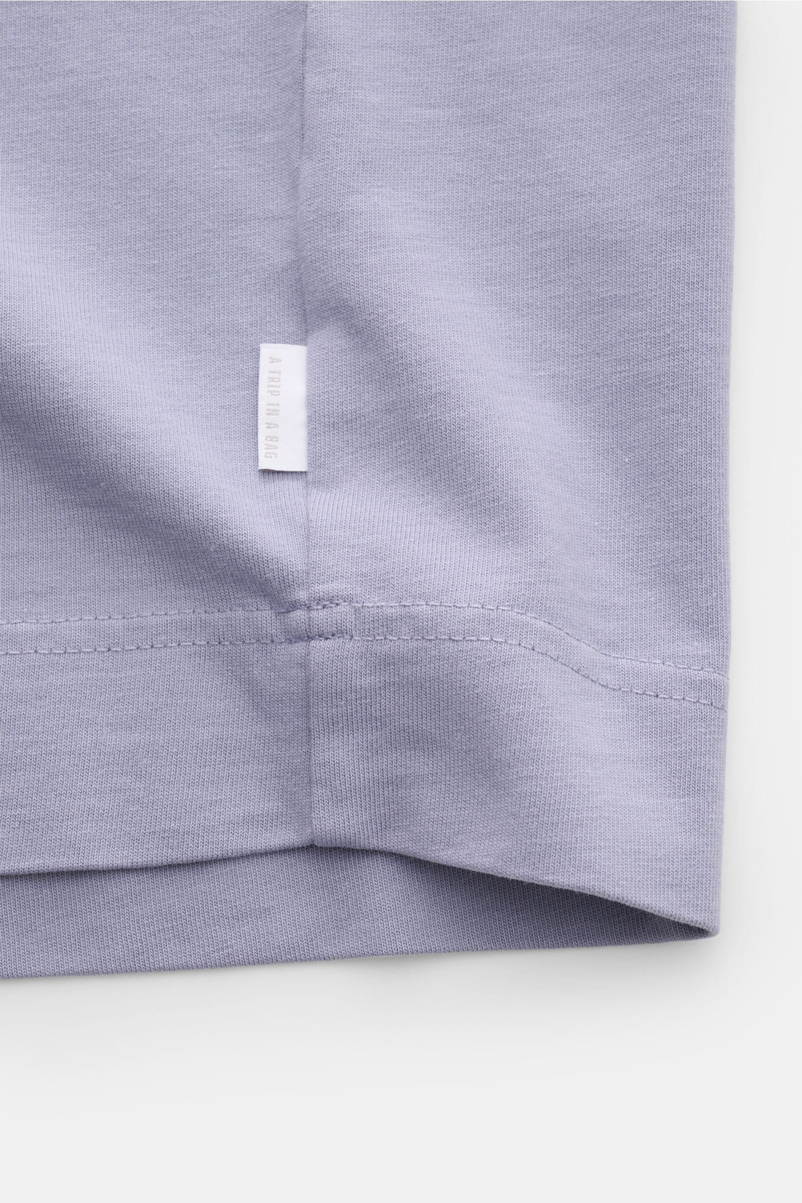 04651/ A trip in a bag Rundhals-T-Shirt lavender, Detailaufnahme Saum mit kleinem Weblabel, schwere Baumwolle, Regular Fit, griffige Haptik