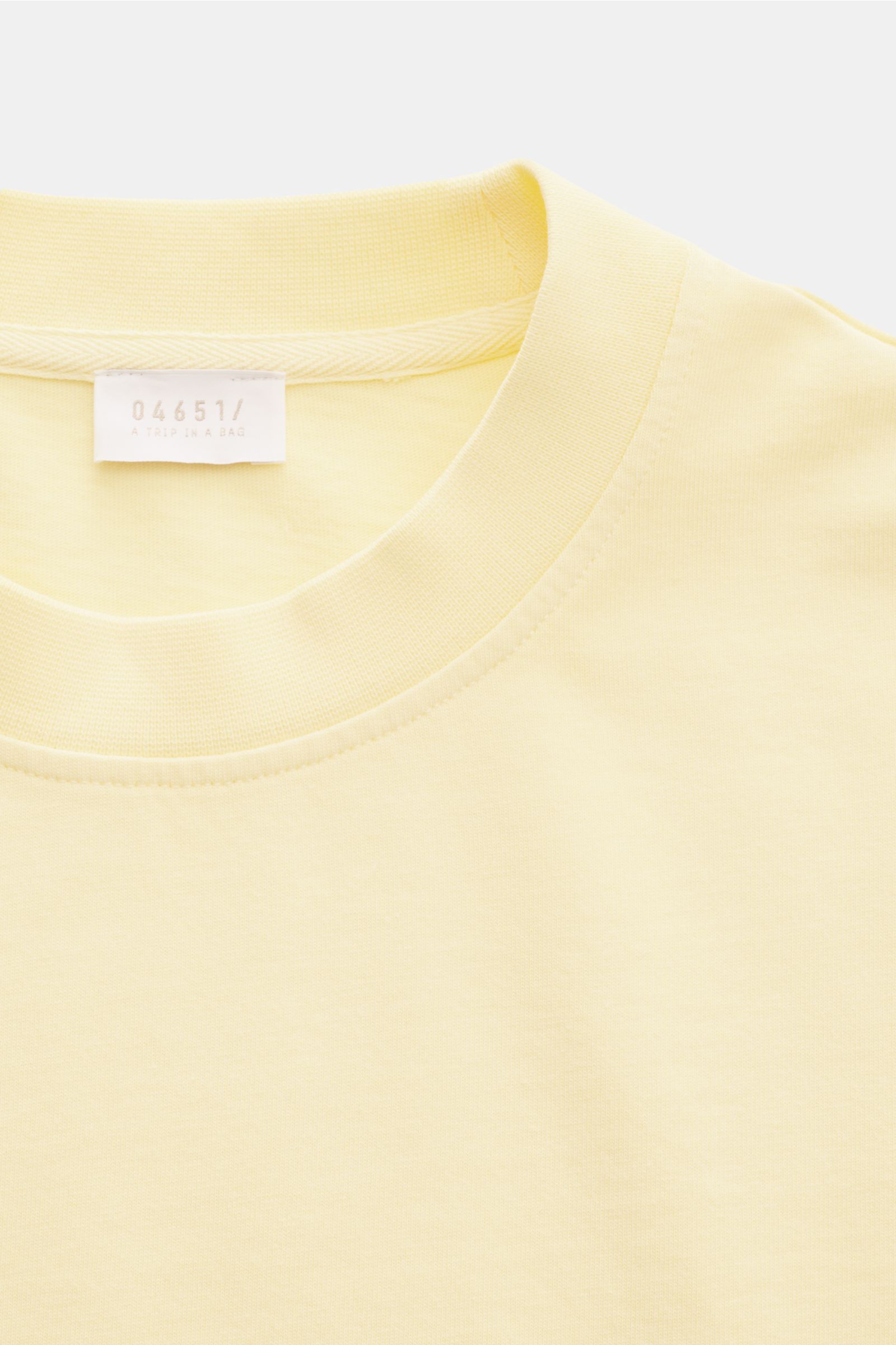 04651/ A trip in a bag Rundhals-T-Shirt pastellgelb in Nahaufnahme, robustes Basic aus schwerem Baumwoll-Jersey mit kleinem Weblabel.
