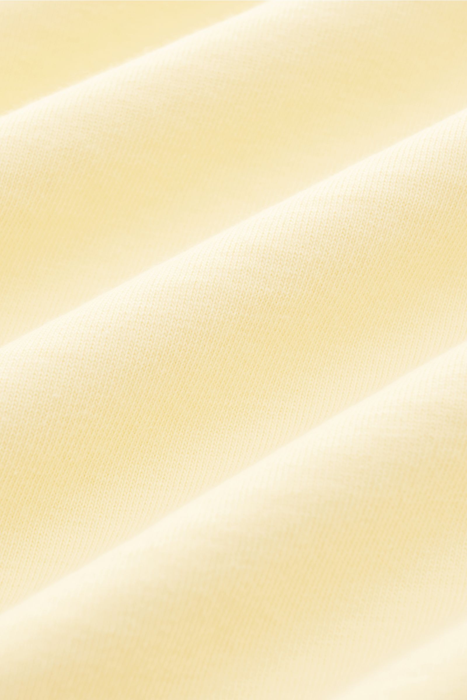 04651/ A trip in a bag Rundhals-T-Shirt pastellgelb aus schwerem Baumwoll-Jersey, Detailaufnahme der griffigen Stoffstruktur in Nahaufnahme.