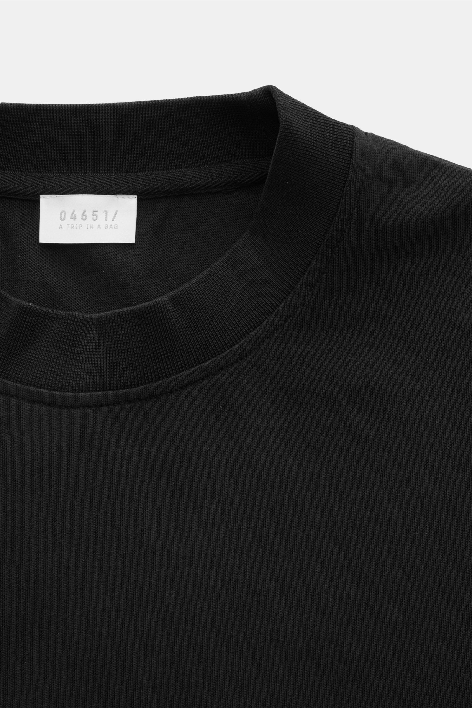 Schwarzes 04651/ A trip in a bag Rundhals-T-Shirt aus schwerem Baumwoll-Jersey, Front nah, mit kleinem Weblabel und Regular Fit.