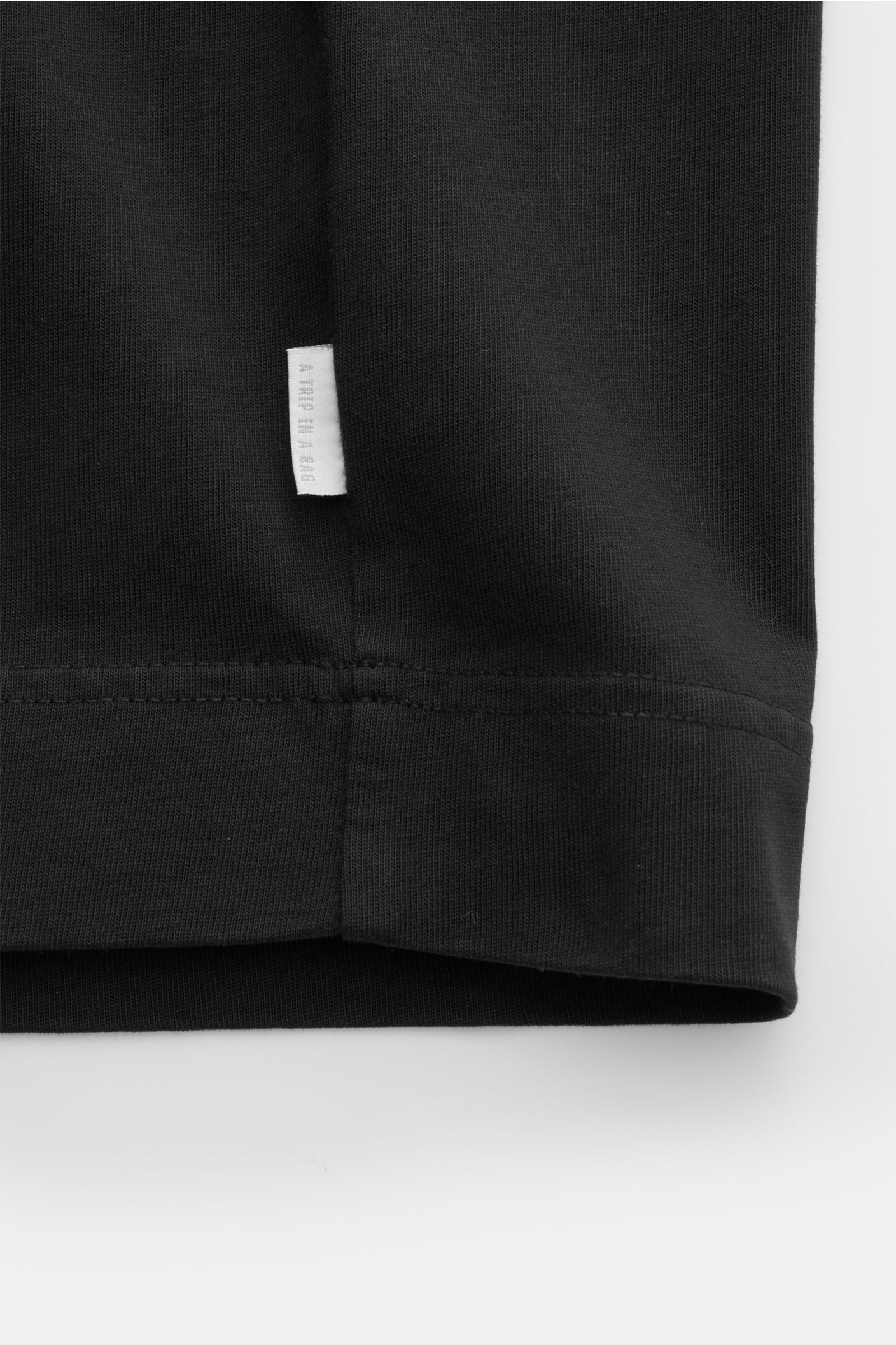 04651/ A trip in a bag Rundhals-T-Shirt schwarz, Detailaufnahme Saum mit kleinem Weblabel, robuste Baumwolle, schwere Qualität, Regular Fit.