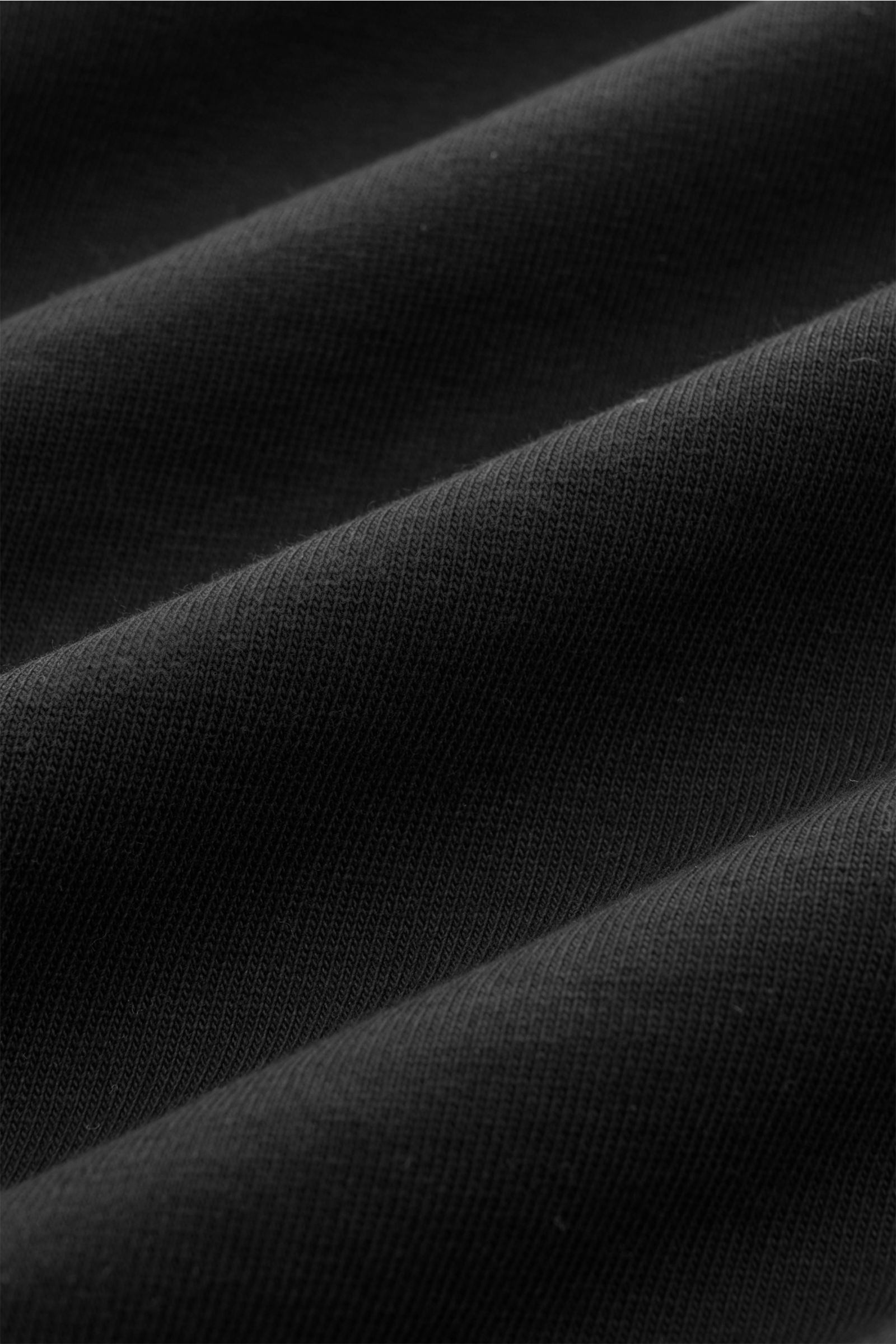 Nahaufnahme des schwarzen 04651/ A trip in a bag Rundhals-T-Shirts aus schwerem Baumwoll-Jersey mit leicht griffiger Haptik und kleinem Weblabel.