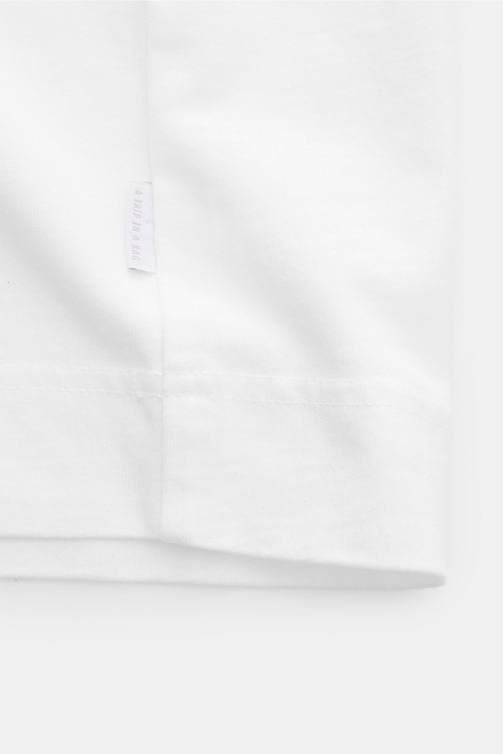 04651/ A trip in a bag T-Shirt 'Nunu' weiß, Detailansicht Saum und Label, Basic mit Print-Akzent, reine Baumwolle, weicher Griff, Regular Fit, Rundhalsausschnitt, rückwärtiger Print.